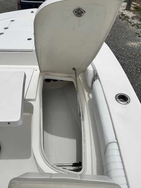 An open storage compartment on a boat with white upholstery and gray flooring.