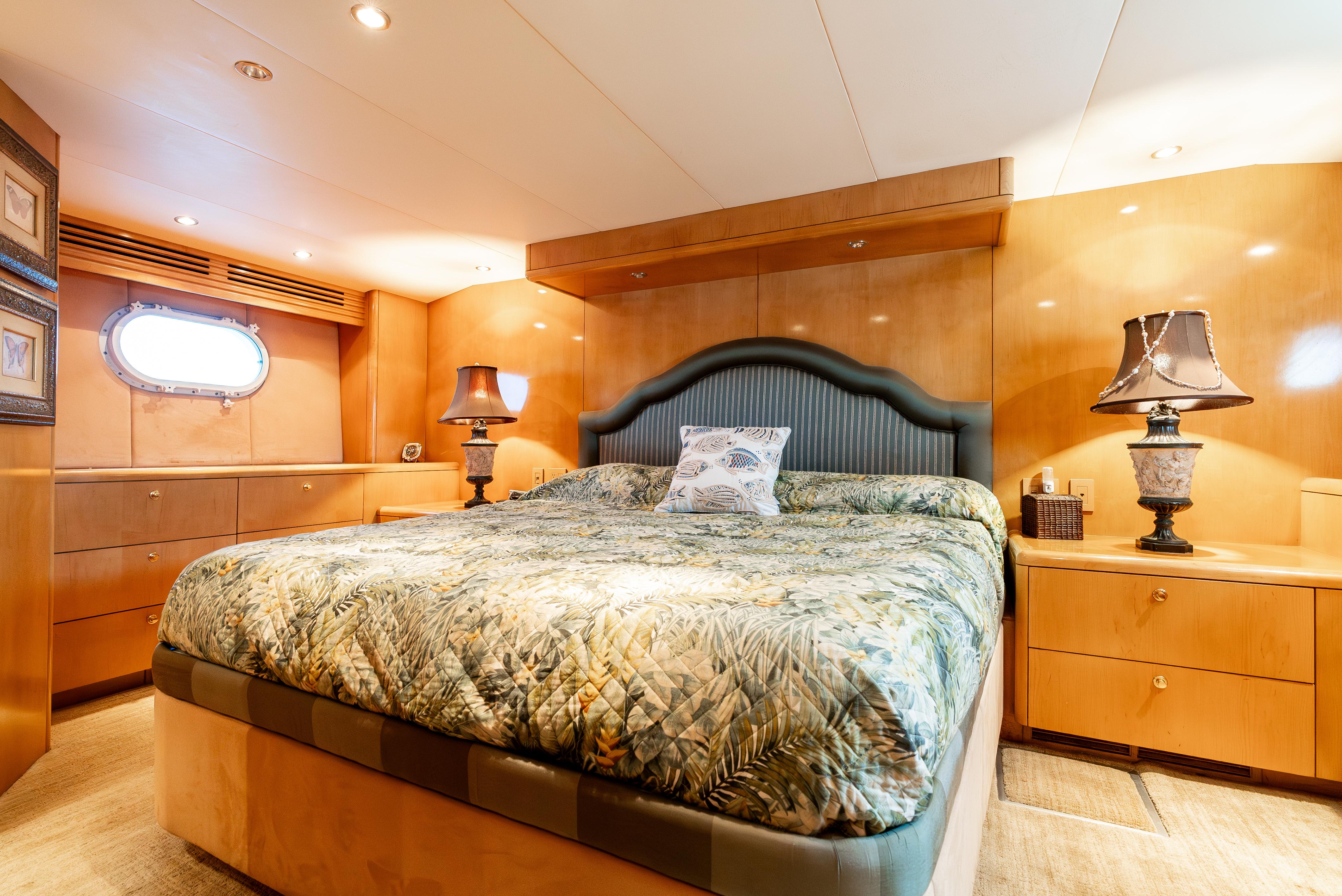 Luxurious bedroom interior of 2000 Hatteras 70 Convertible yacht with elegant decor and lighting.
