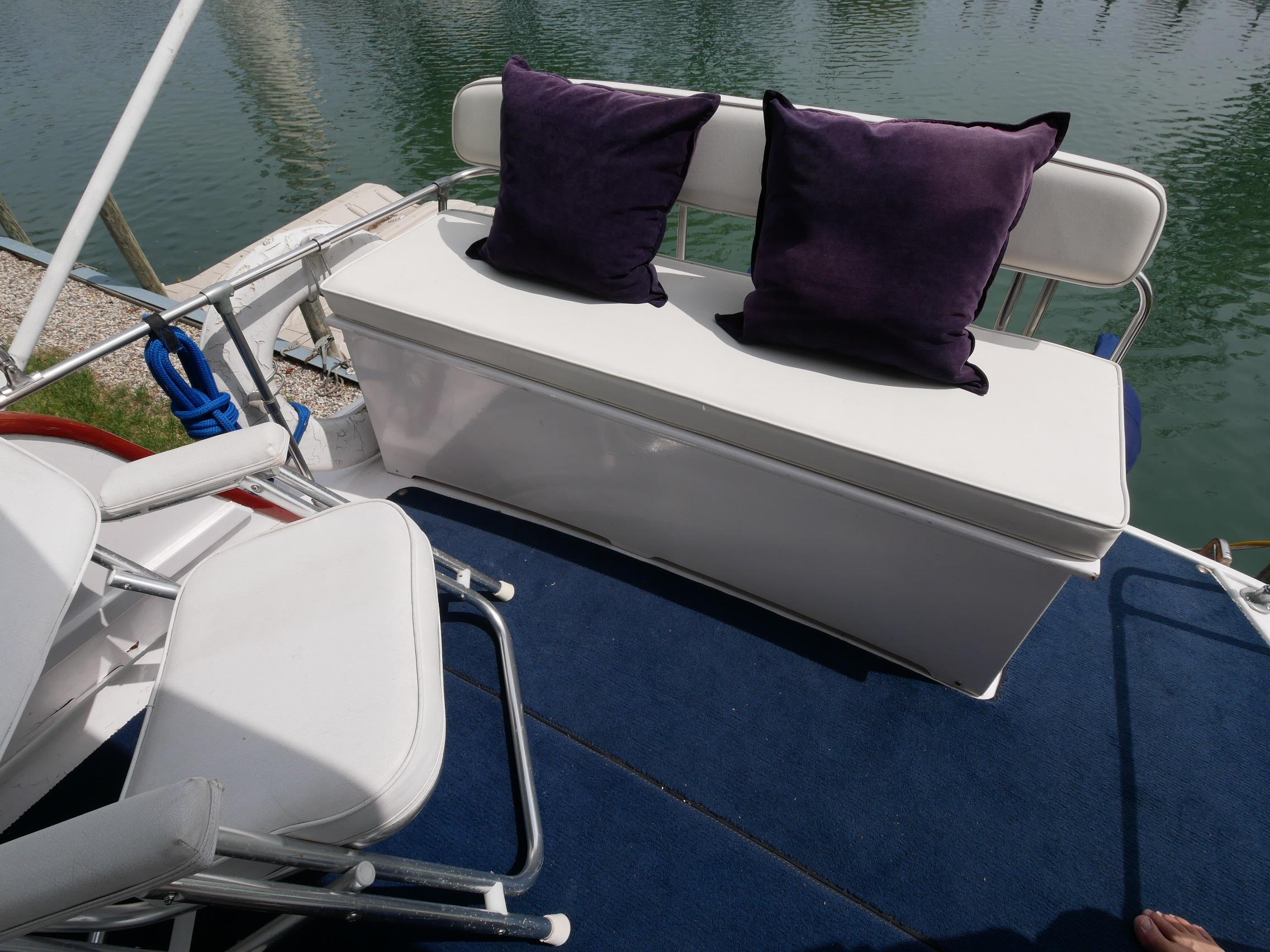 1964 Egg Harbor 37 Convertible Sedan boat seating area with white cushions and purple pillows.
