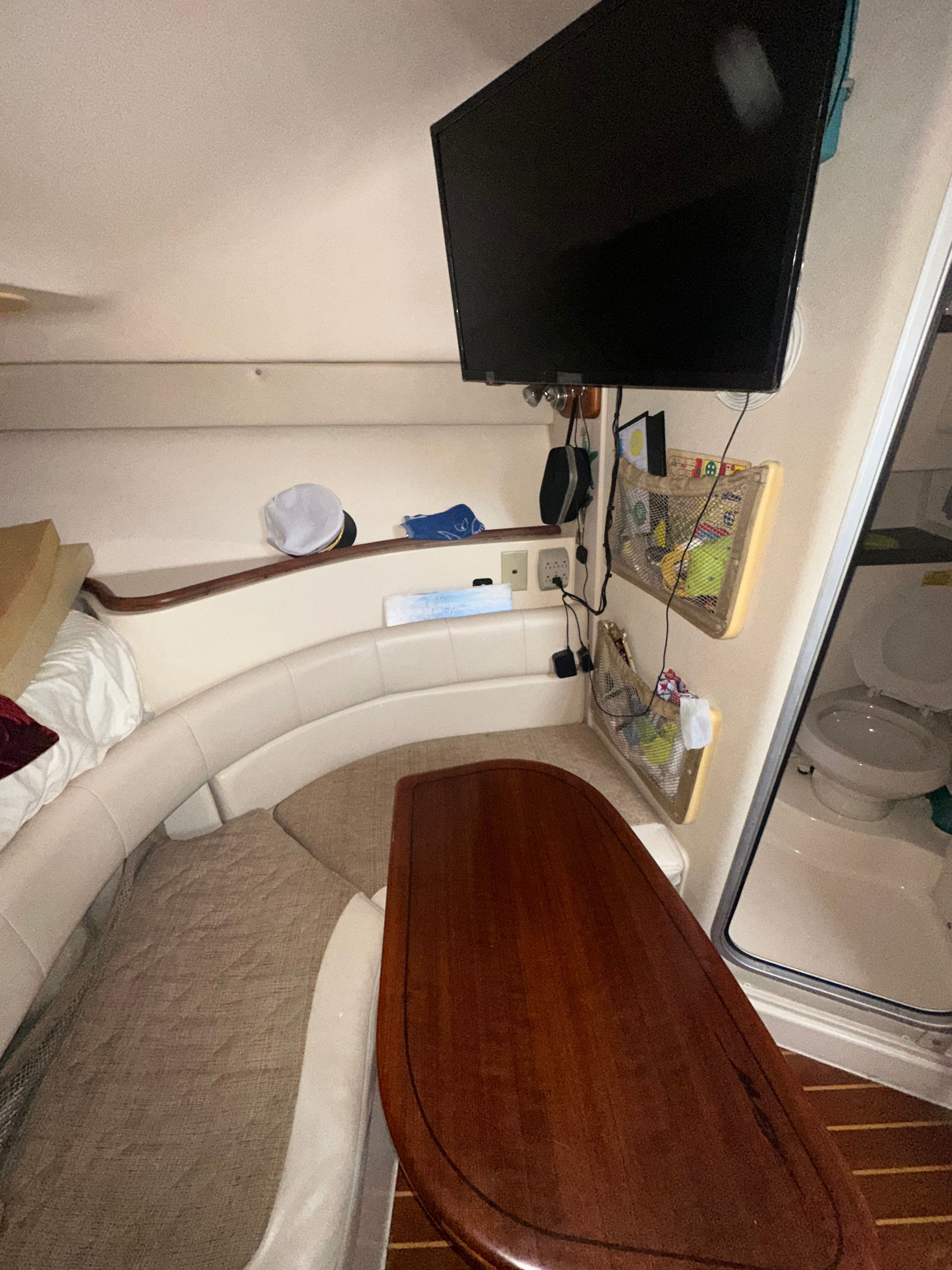 Interior of a 2003 Grady-White Express 330 with seating area, table, and TV.