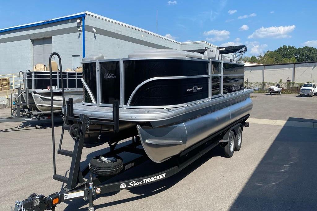 2026 Sun Tracker Party Barge 22 DLX pontoon boat on trailer in parking lot.