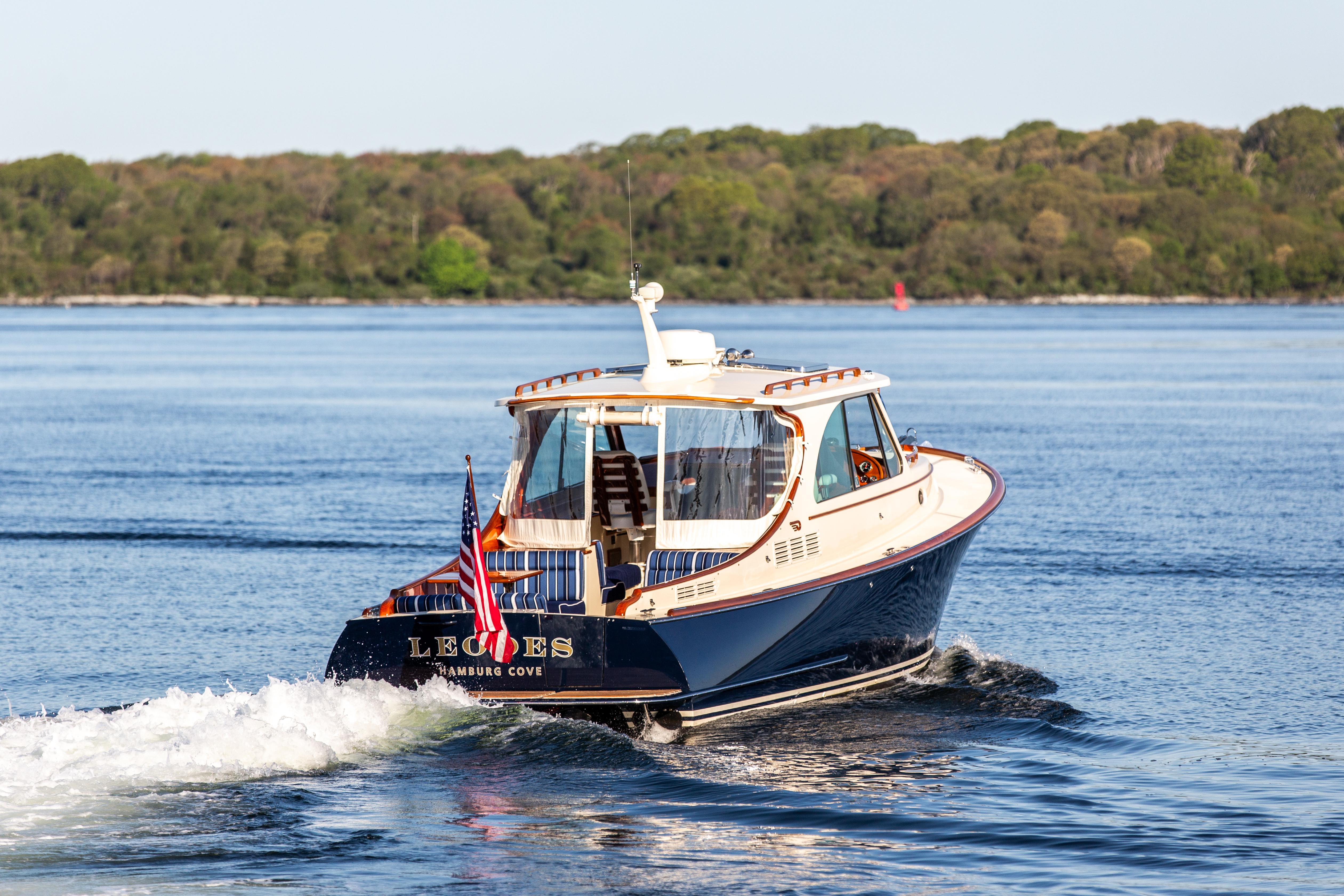 2022 Hinckley Picnic Boat 34 S cruising on a serene lake with lush green shoreline.