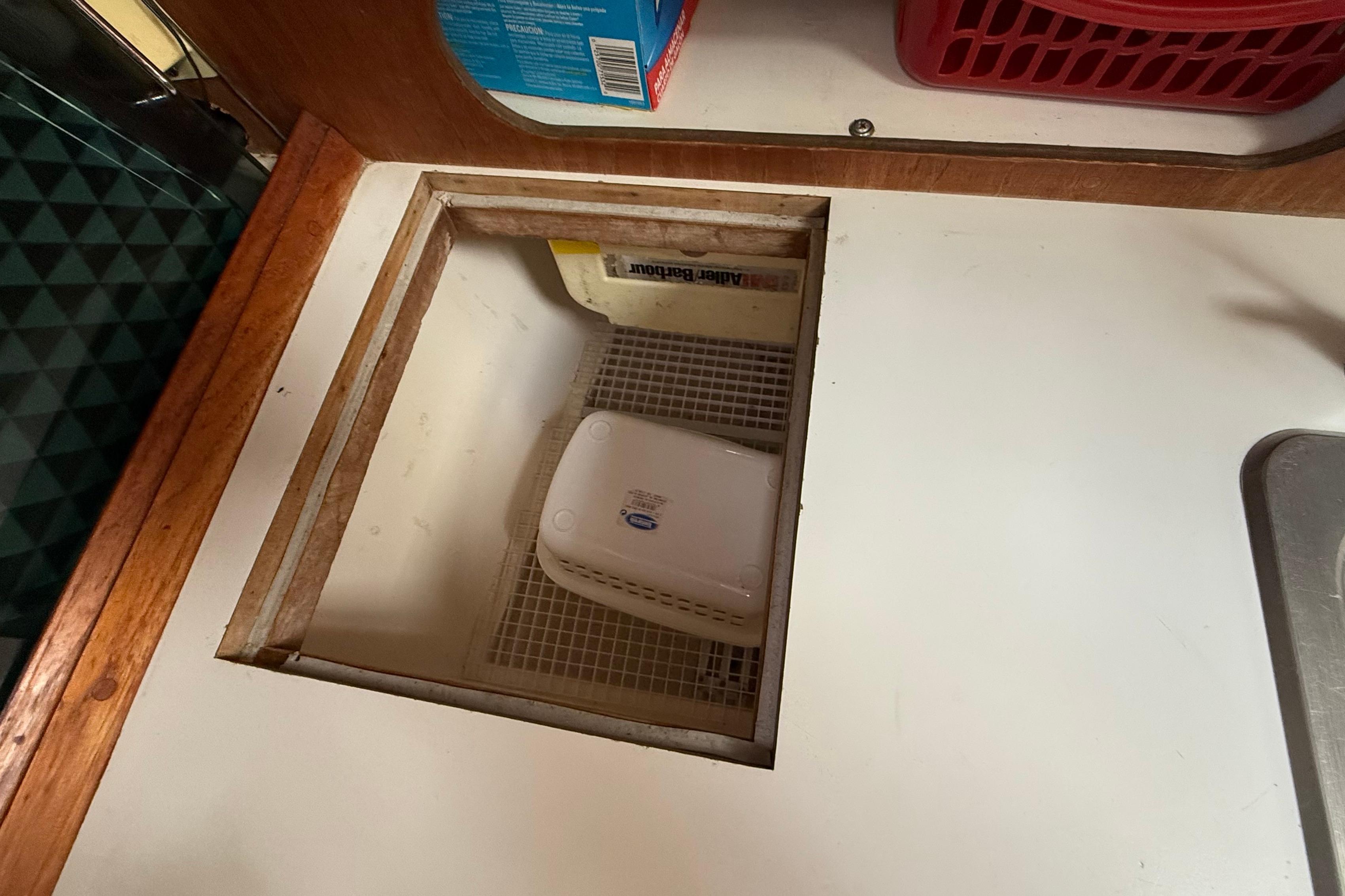 Hidden compartment in 1984 Hunter 31 boat galley with storage container.
