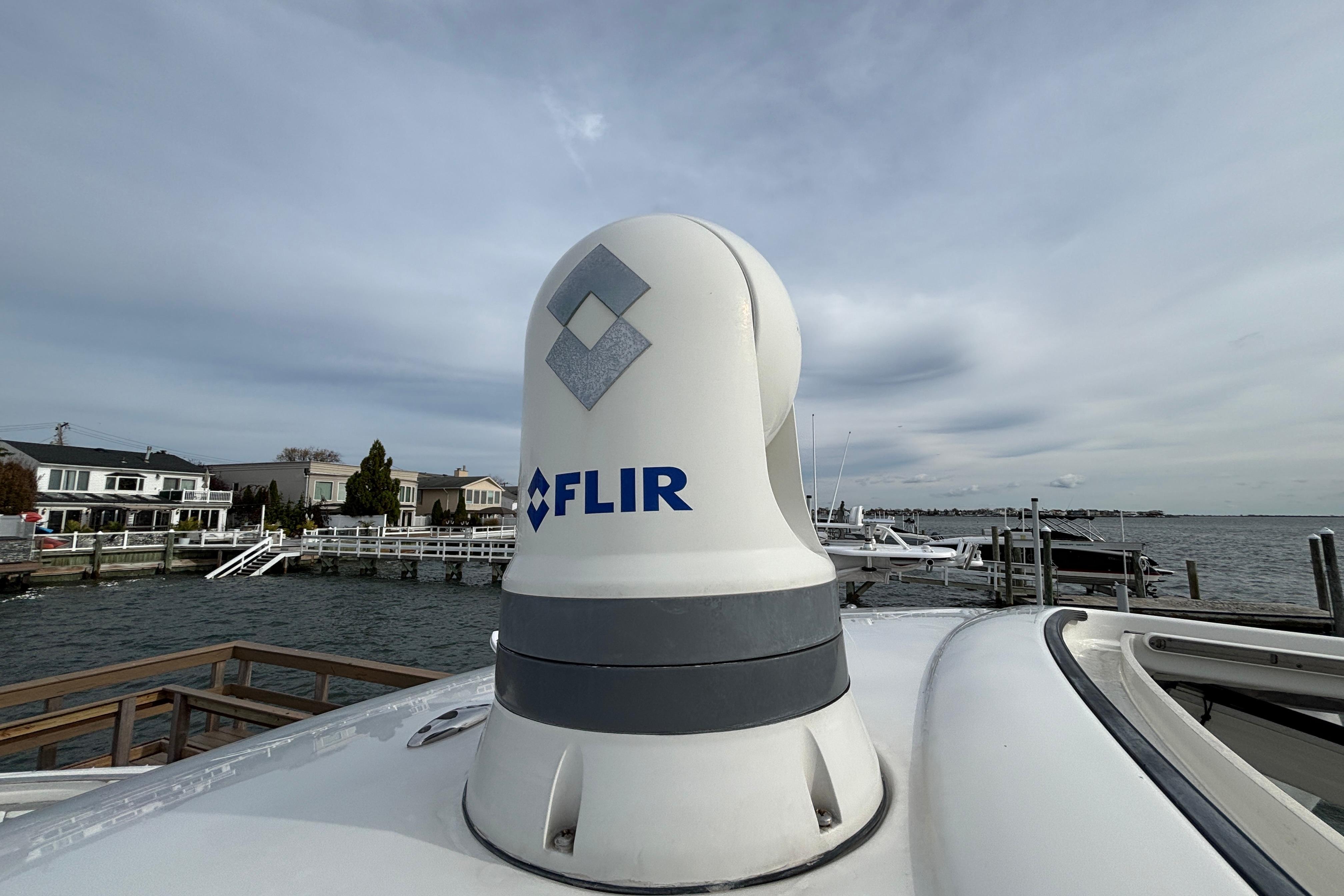 FLIR camera on 2022 Pursuit DC 365 Dual Console boat, docked by waterfront homes.