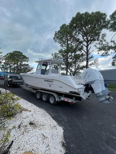 2014 Everglades 325 Center Console boat on trailer, parked outdoors near trees.