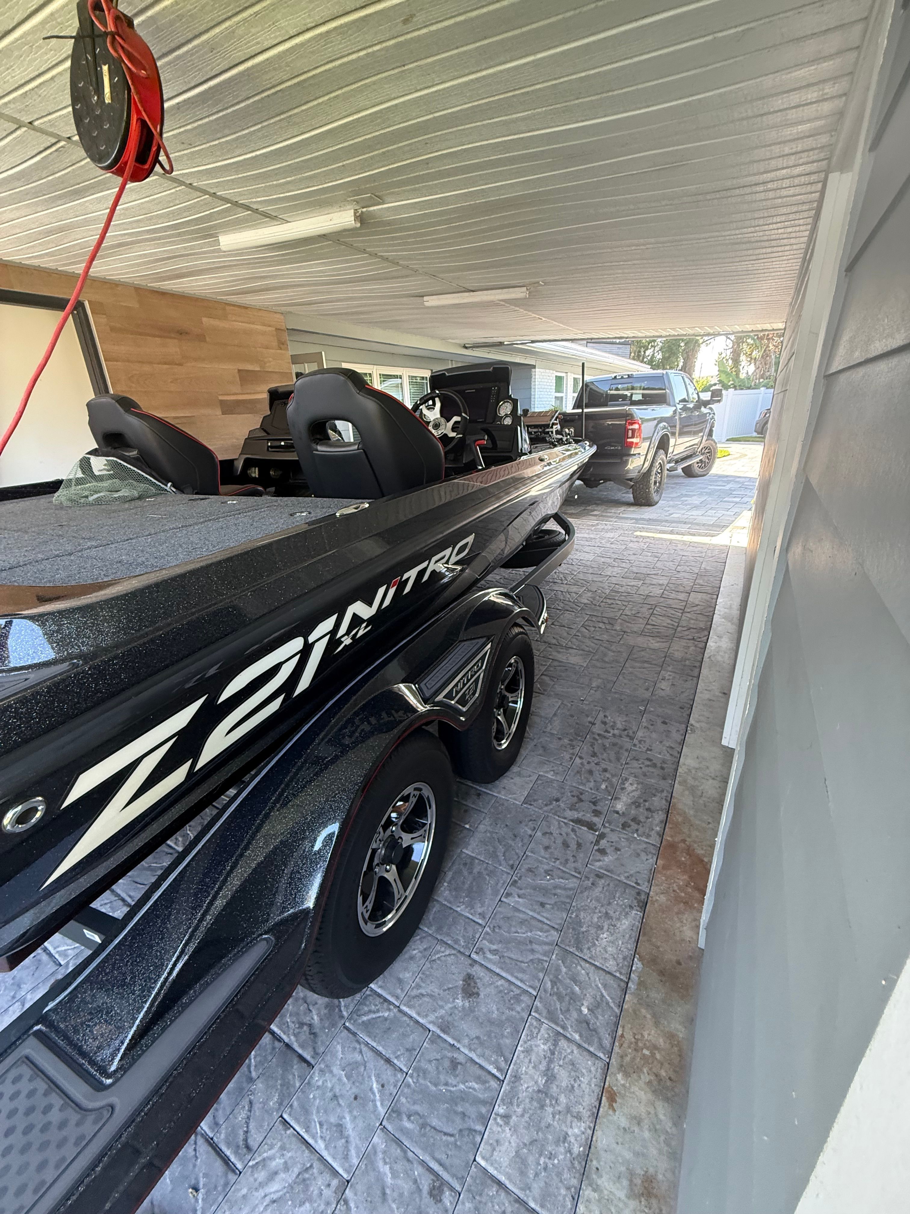 A 2024 Nitra Boats 21 XL Pro on a trailer in a covered driveway.