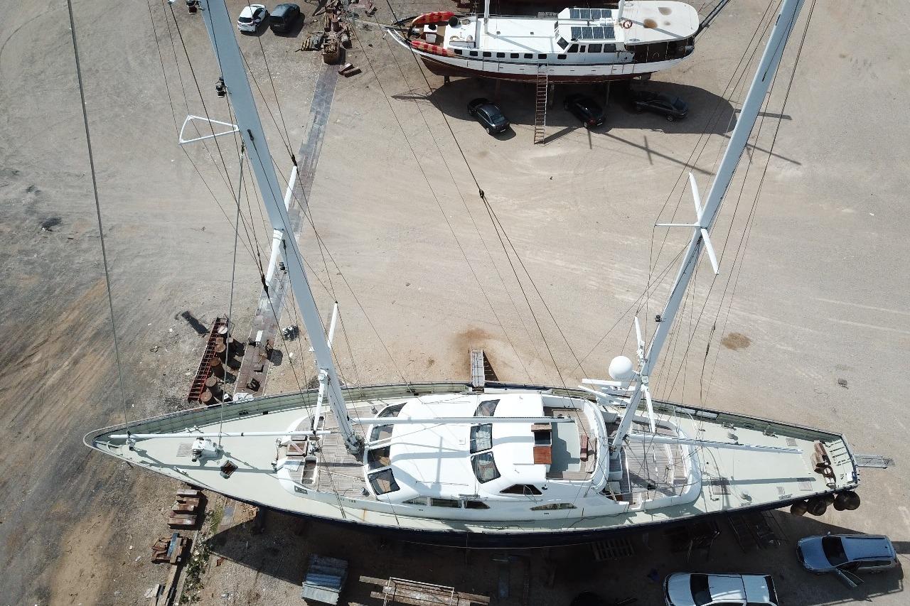 Aerial view of 2001 Ortona Navi 115 yacht on dry dock, showcasing its deck and masts.