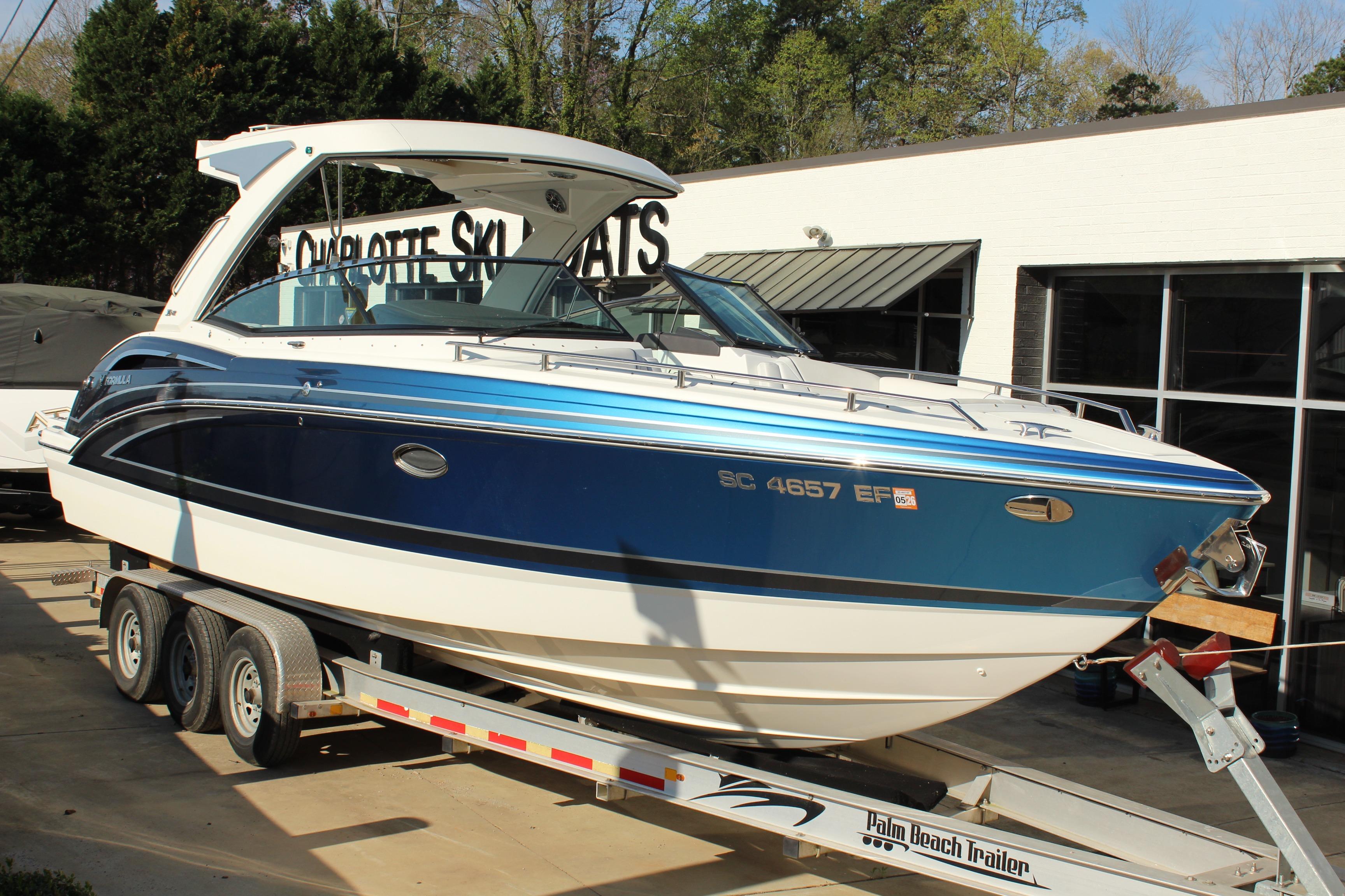 2023 Formula 310 Bowrider I/O boat on trailer, blue and white exterior, parked outside dealership.