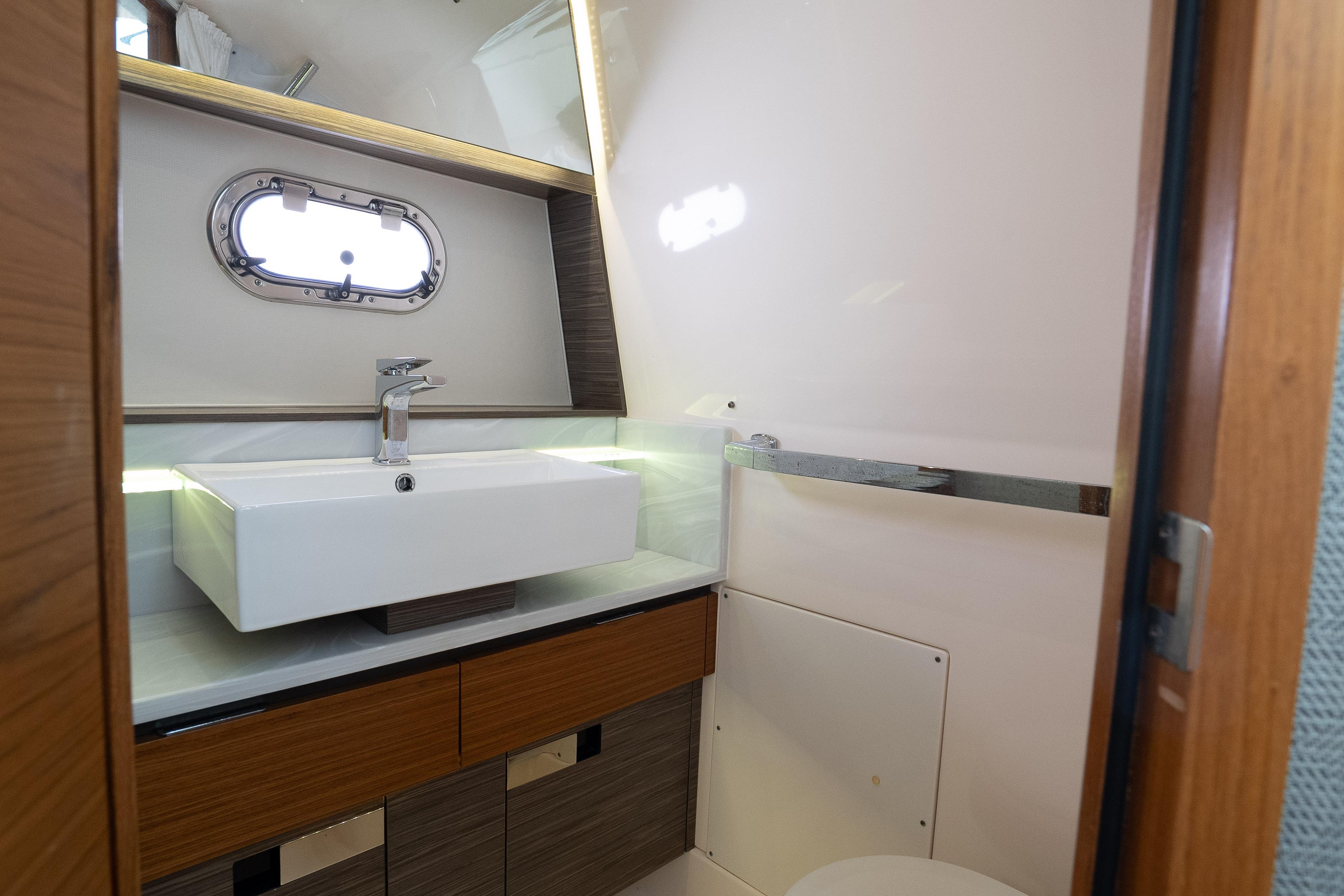 Luxurious bathroom interior of 2019 Tiara Sport 38 LS yacht with modern sink and porthole.