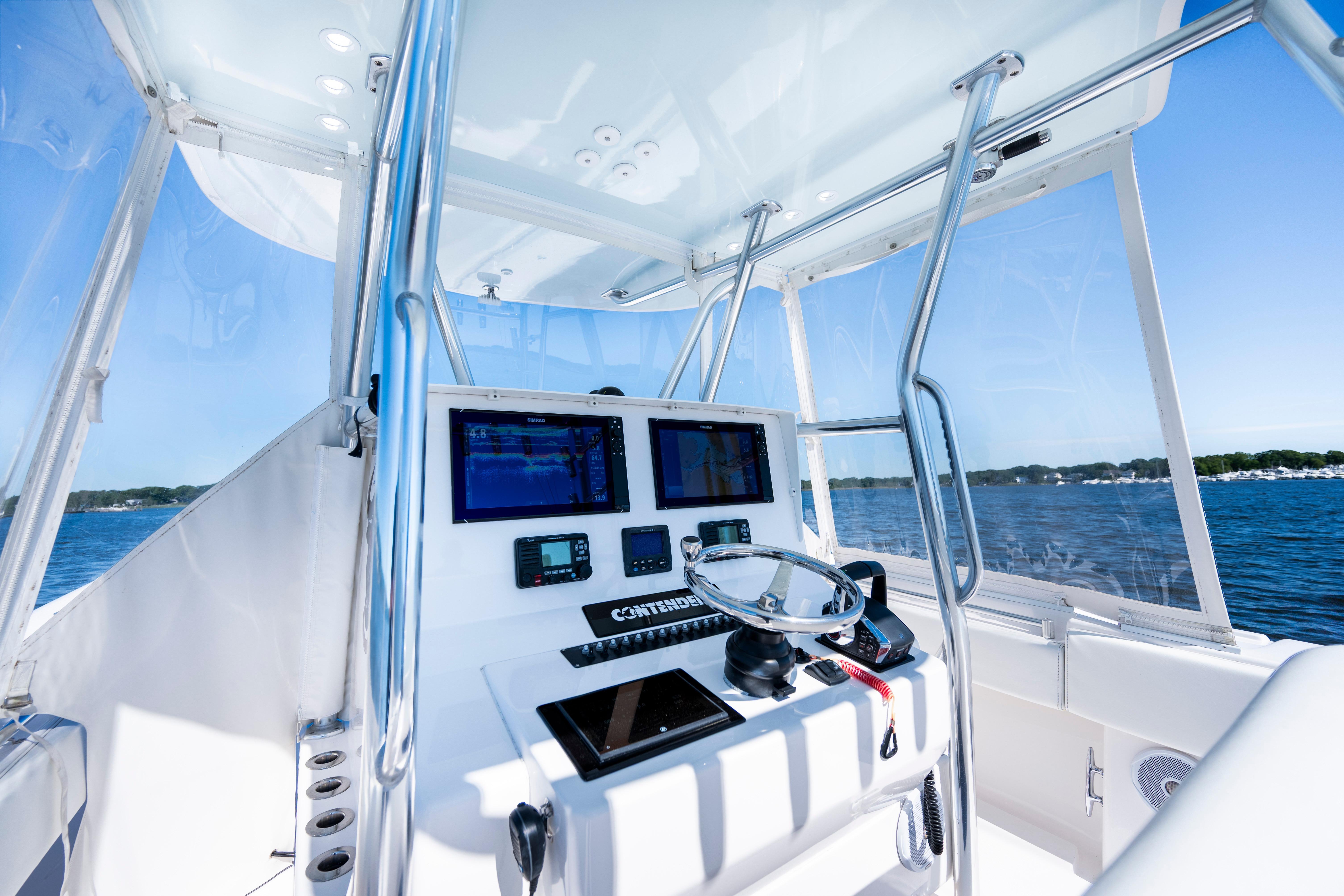 2015 Contender 39 ST boat cockpit with navigation screens and steering wheel on open water.