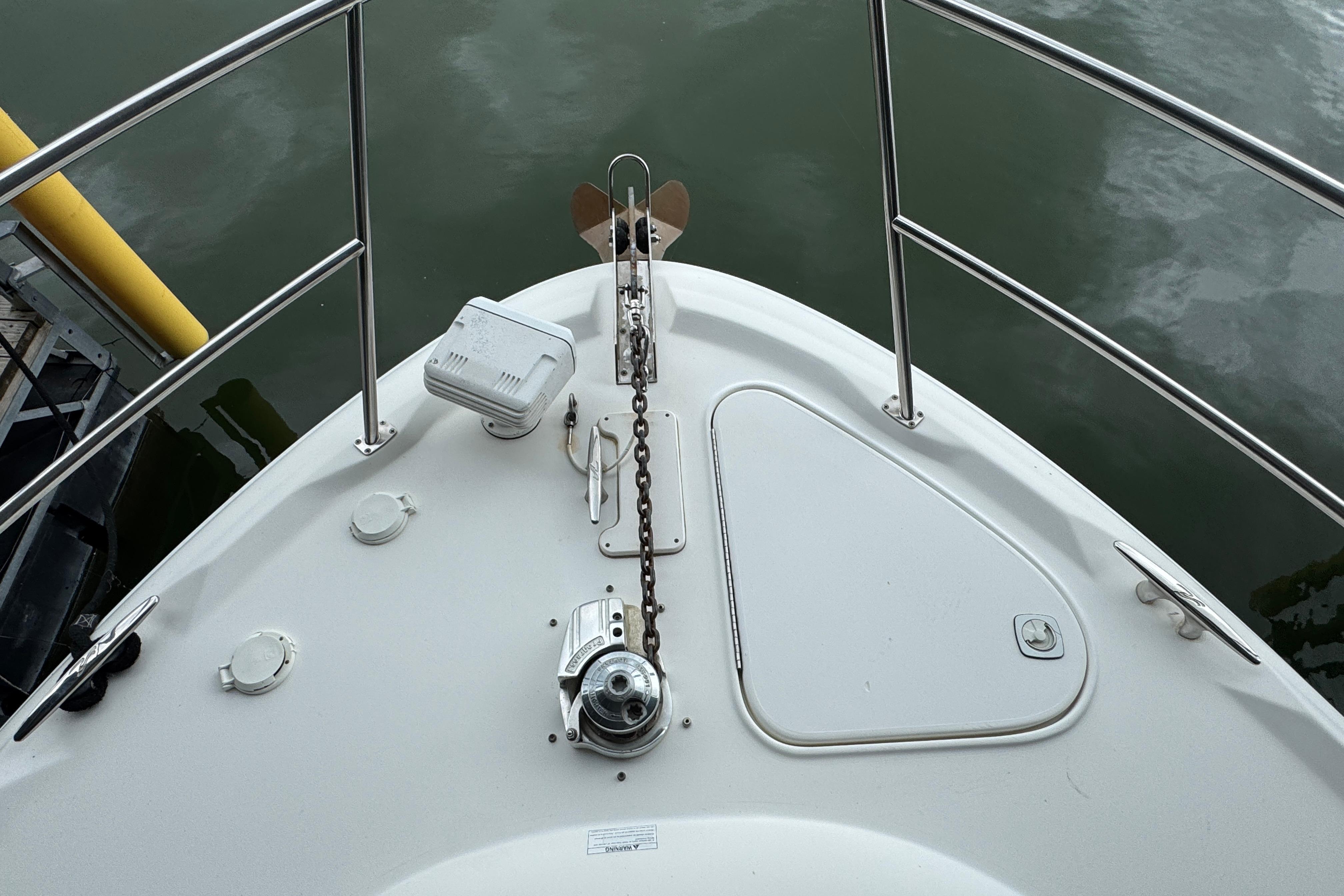 Bow of 2001 Sea Ray 380 Sundancer with anchor and railing, docked on calm water.