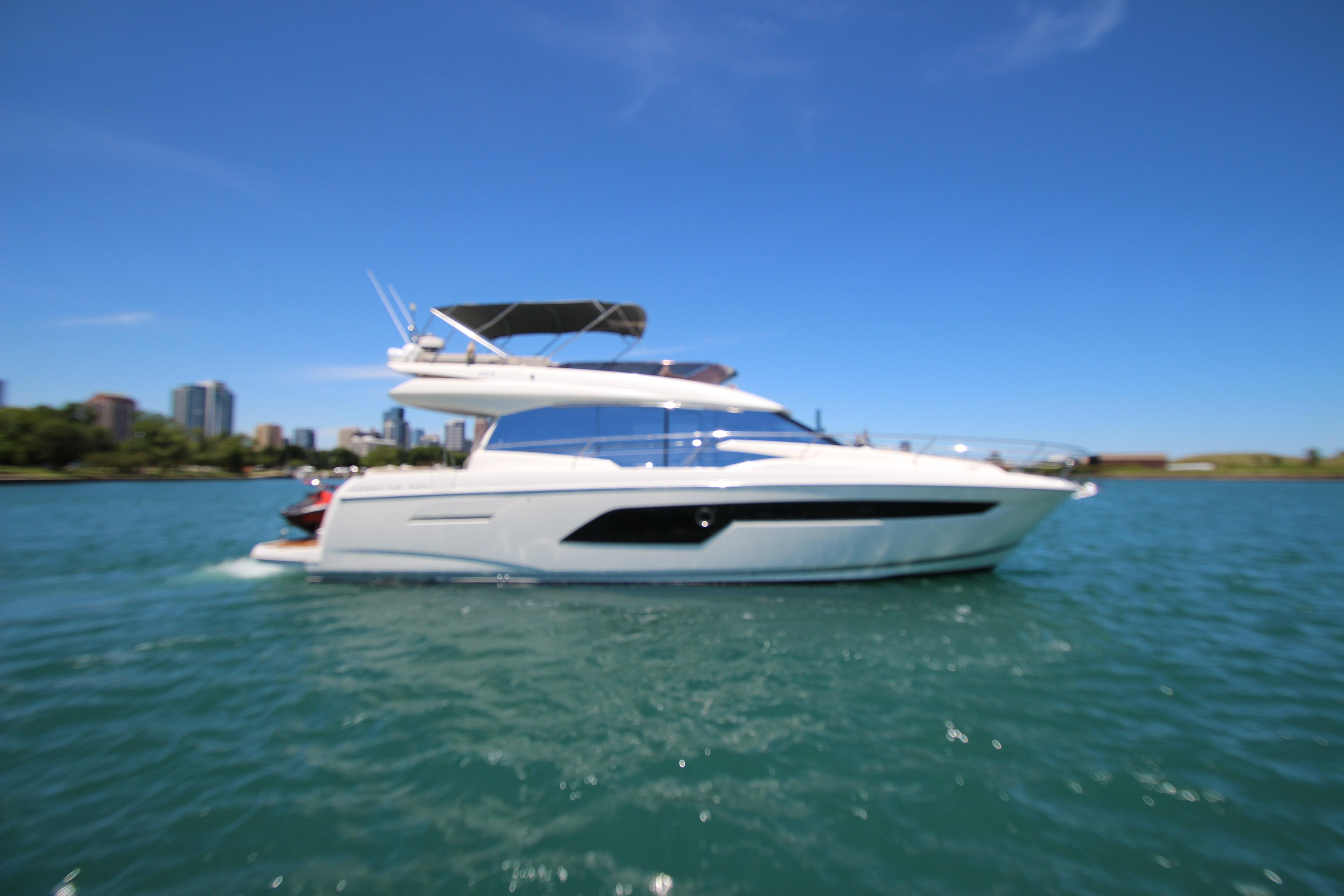 2022 Prestige 520 yacht cruising on a sunny day with city skyline backdrop.