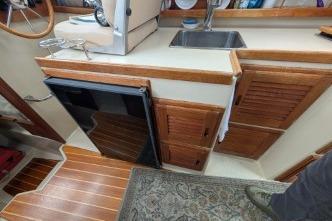 Galley with kitchenette, featuring sink, fridge, and wooden cabinetry.