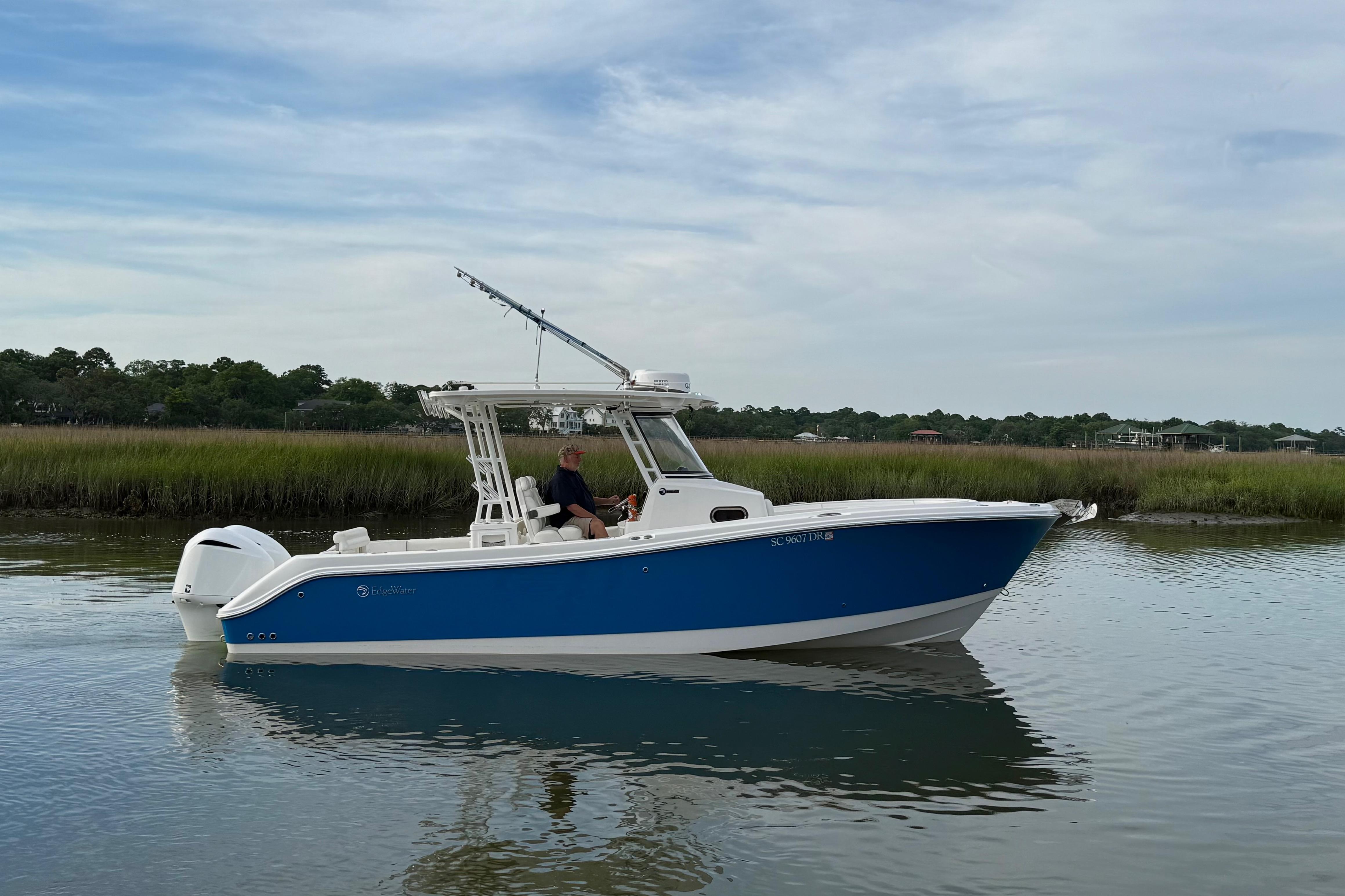 2022 Edgewater 280CC boat cruising on calm water with scenic marshland backdrop.