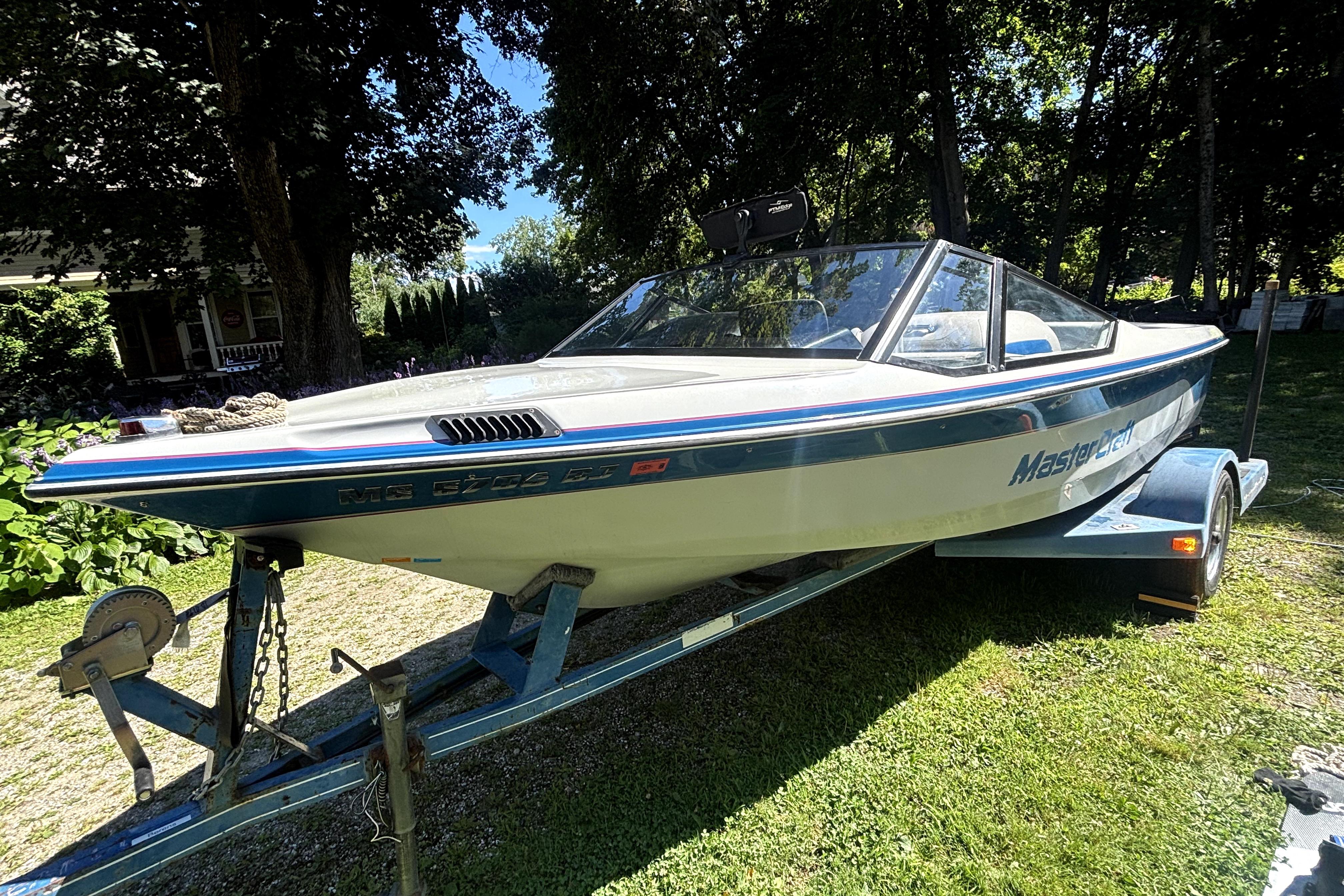 1990 MasterCraft ProStar 190 boat on trailer, parked outdoors in a shaded area.