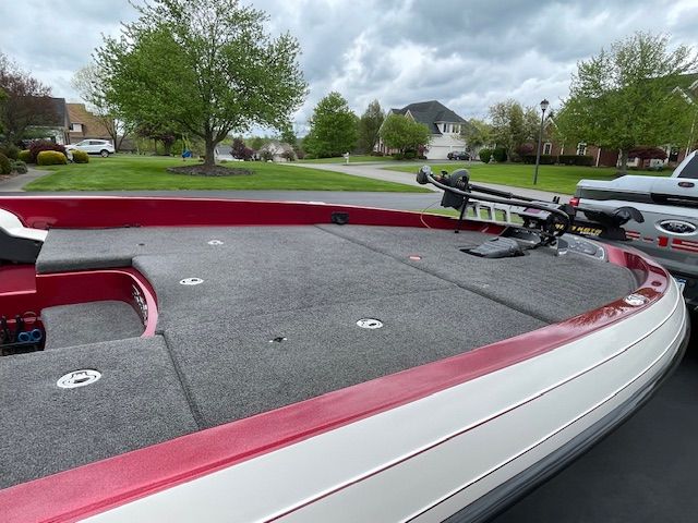 A 2009 Ranger Z520 Comanche boat with a red and gray deck, parked in a residential area.