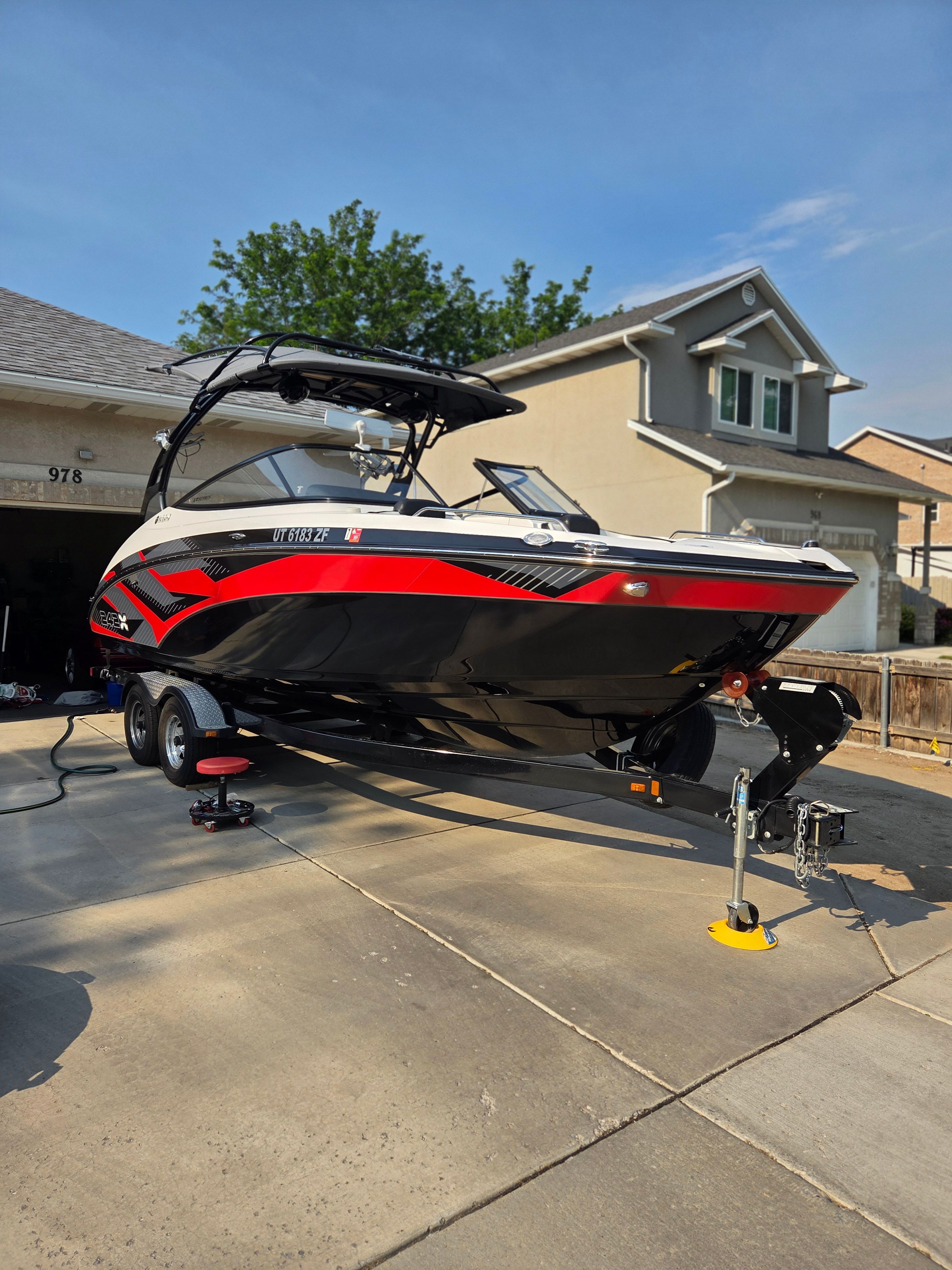 A 2016 Yamaha 242X E-Series boat on a trailer in a driveway.