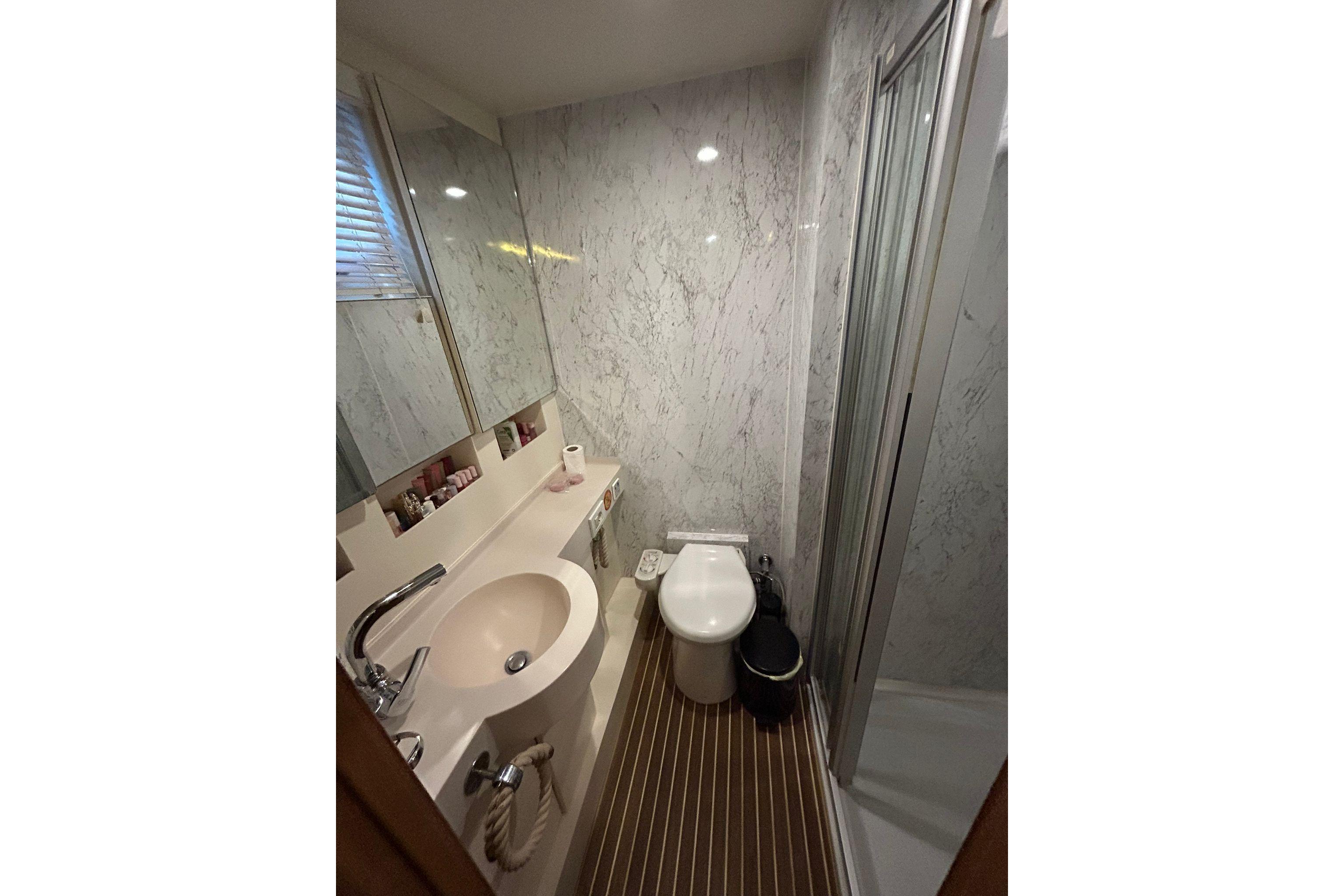 Compact bathroom with marble walls, modern fixtures, and a shower in a 2009 Custom model 68.