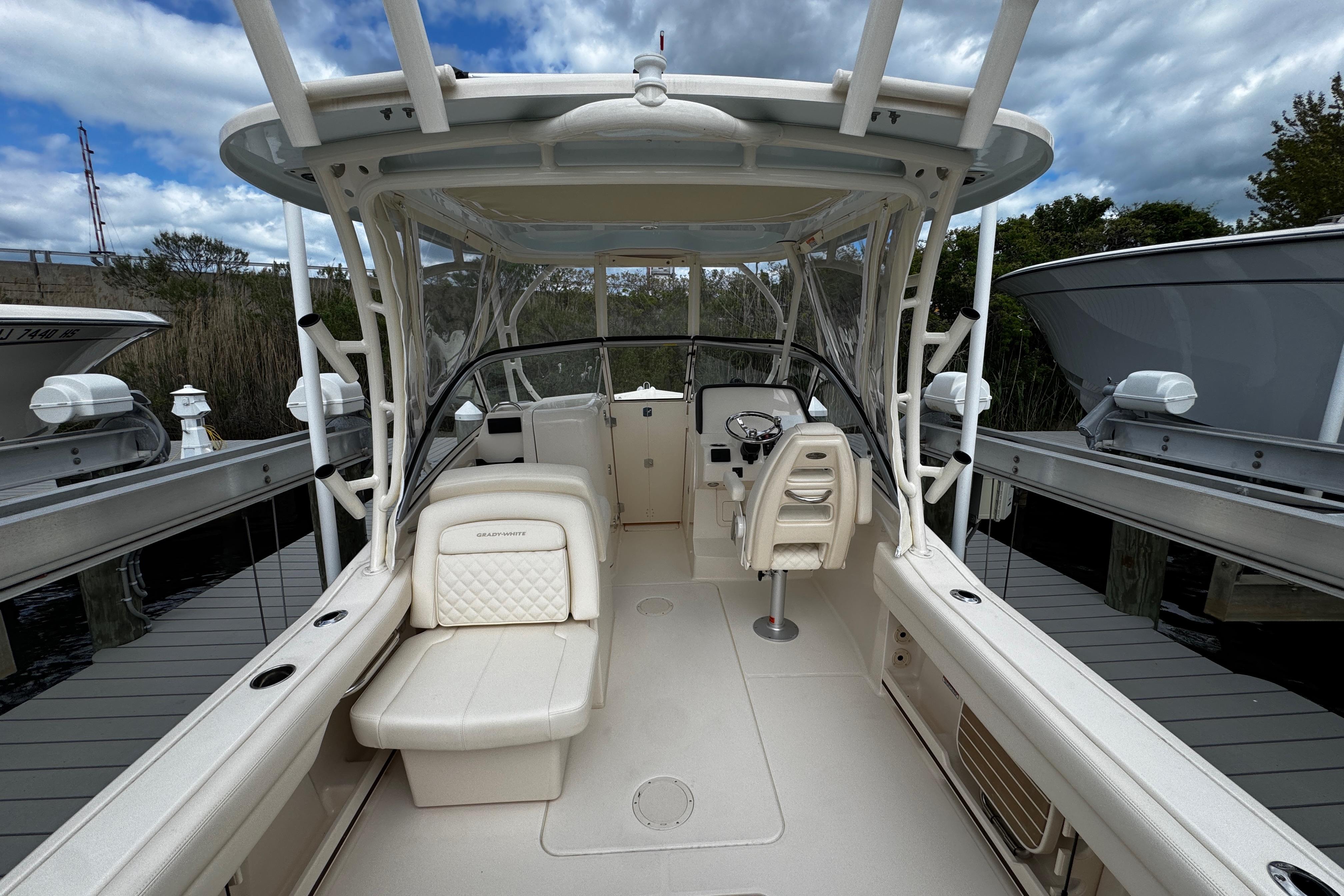 2026 Grady-White Freedom 235 boat interior, featuring seating and helm, docked under cloudy skies.