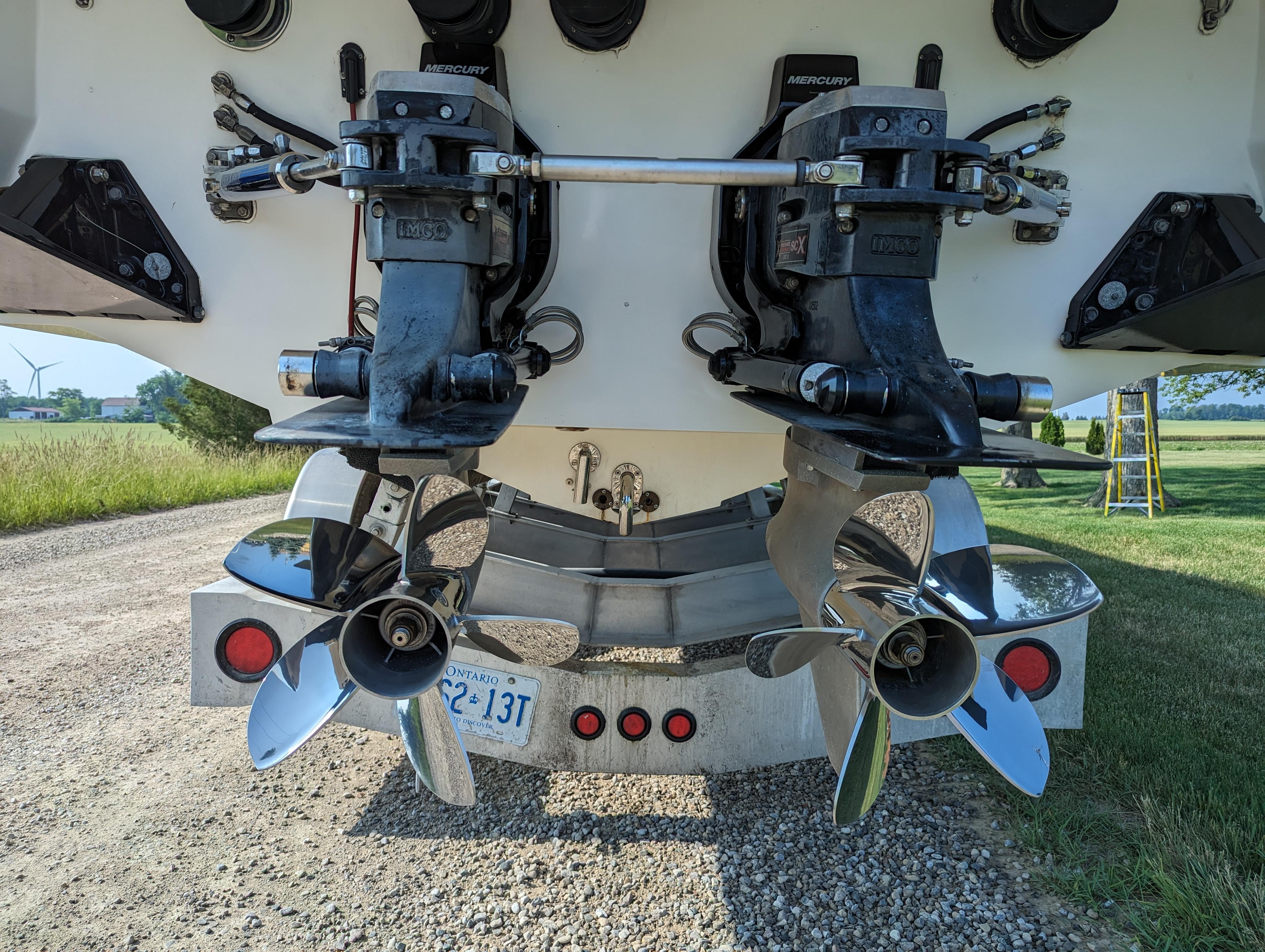 Twin propellers on a 2006 Fountain 42 boat, parked on a gravel path.