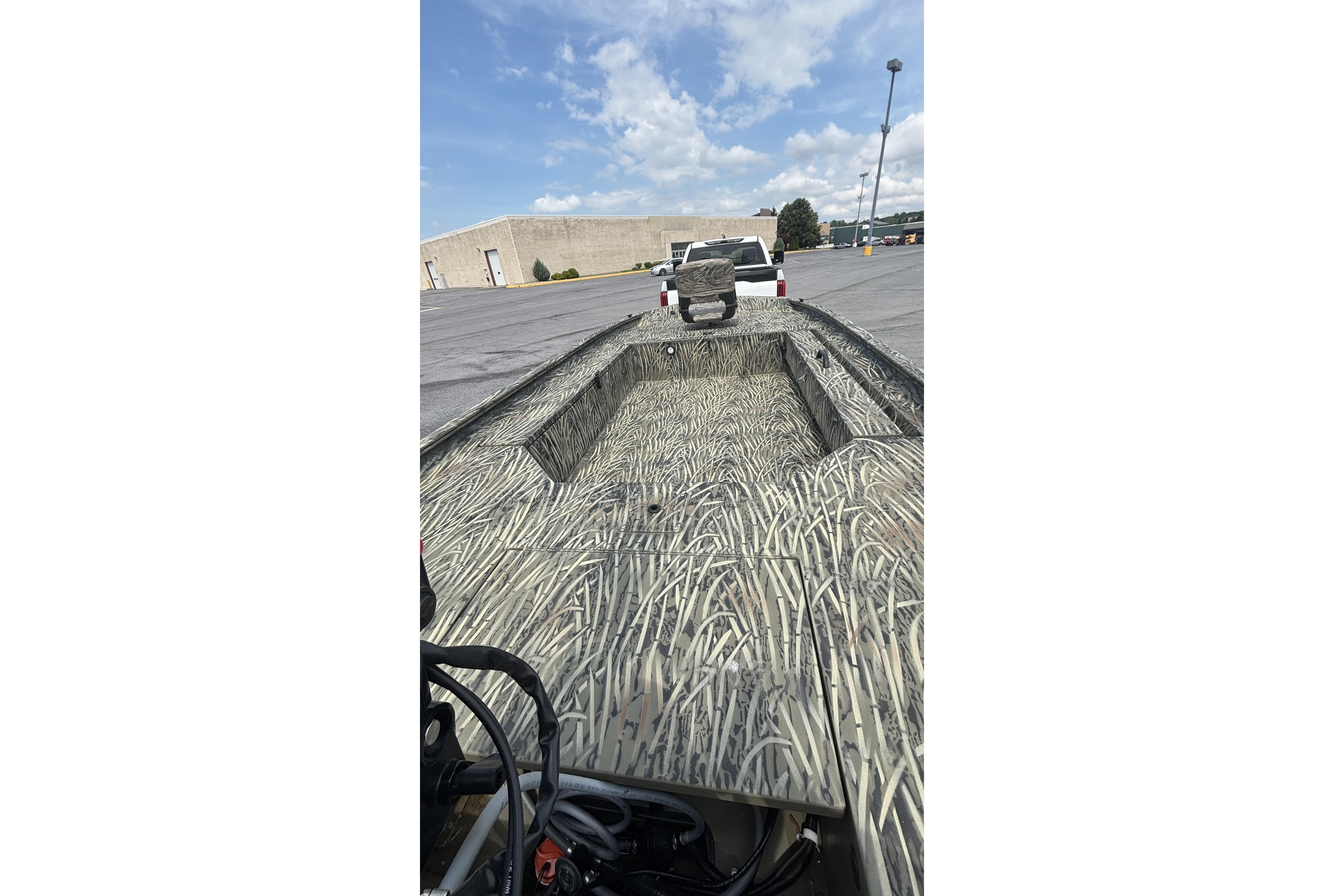 2026 Tracker Grizzly 1654 T Sportsman boat with camouflage design in a parking lot.