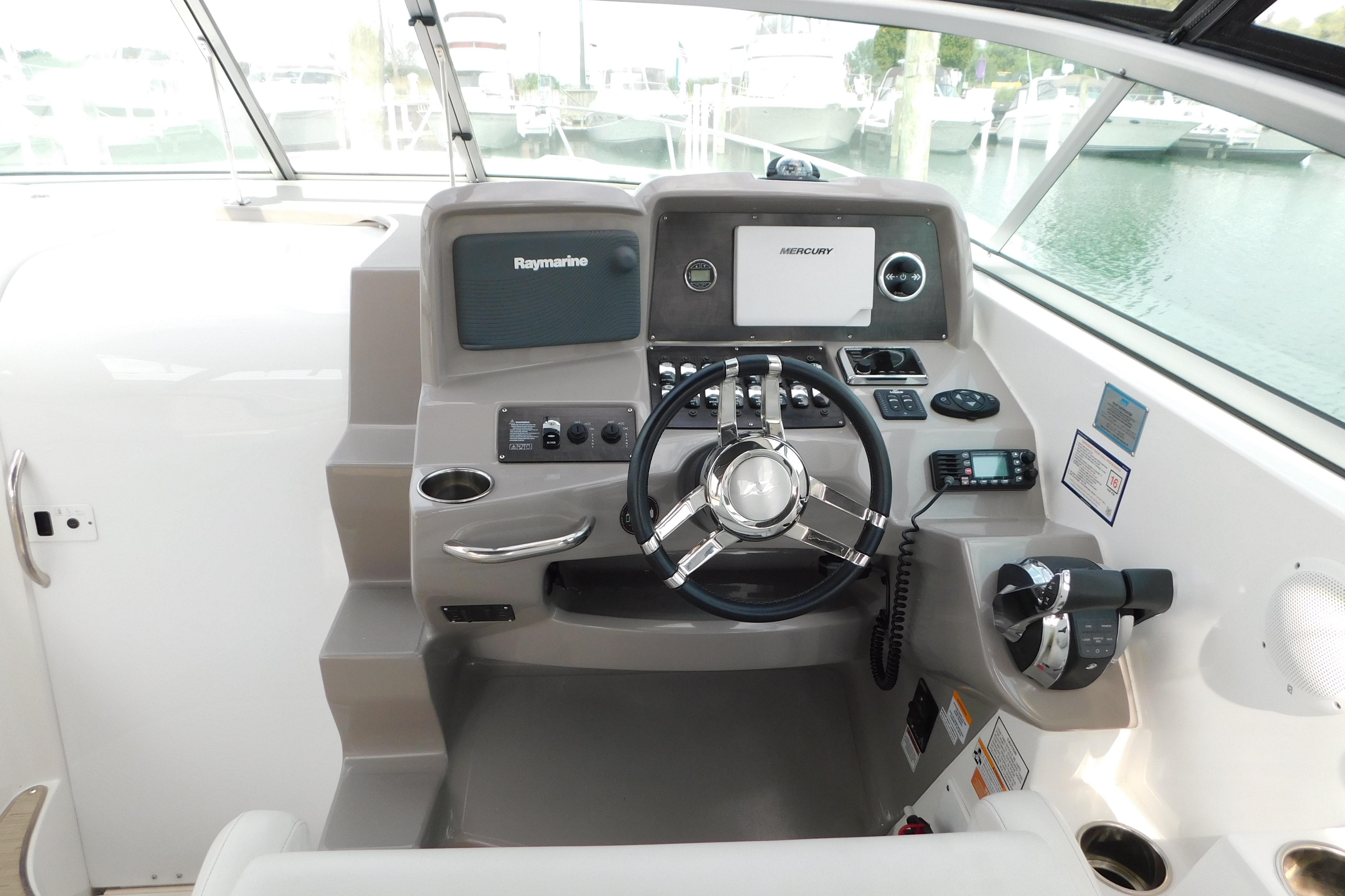 2017 Rinker EX 320 boat helm with Raymarine and Mercury controls, docked at marina.