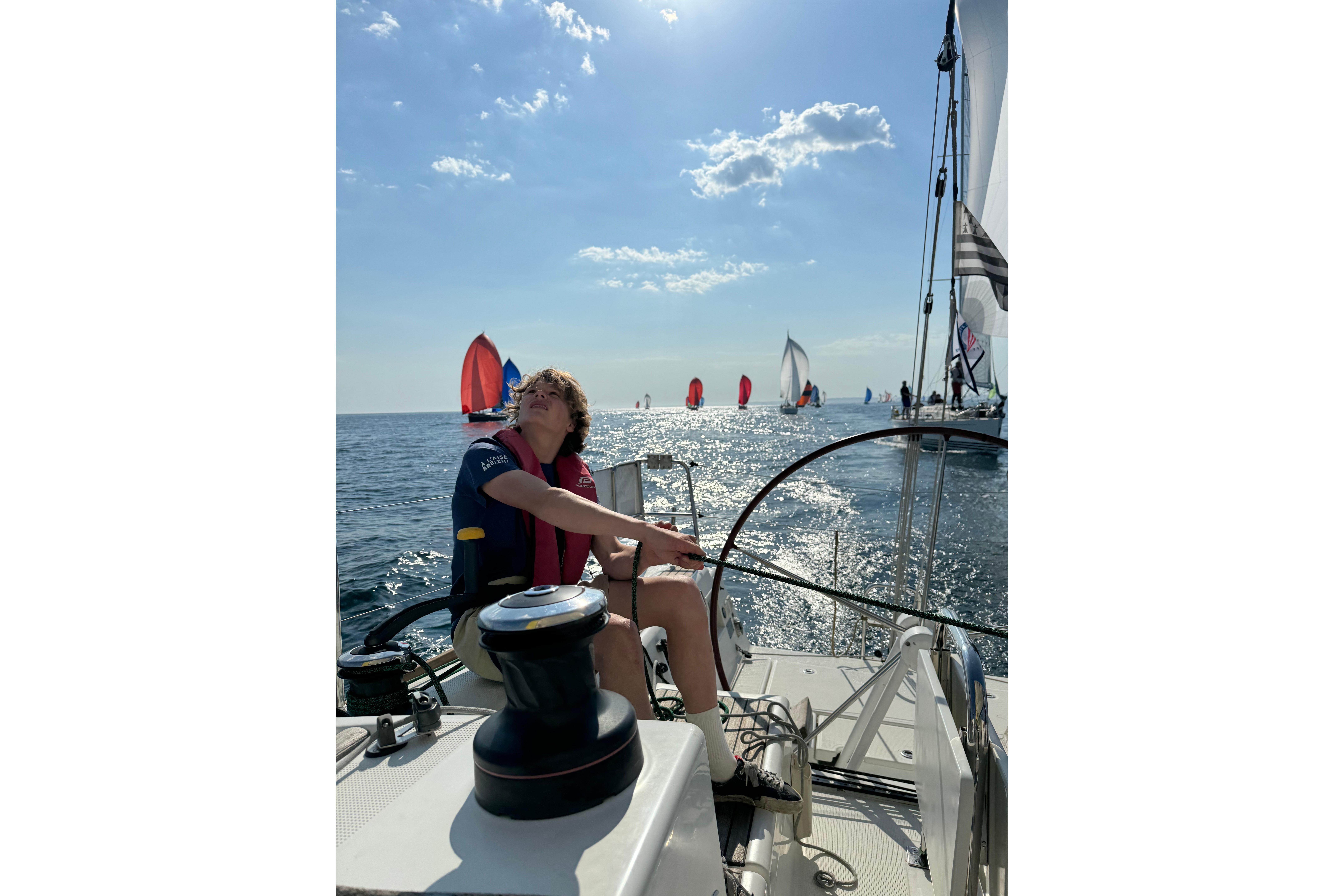 Person sailing a 2011 Beneteau First 35 yacht on a sunny day with other boats nearby.