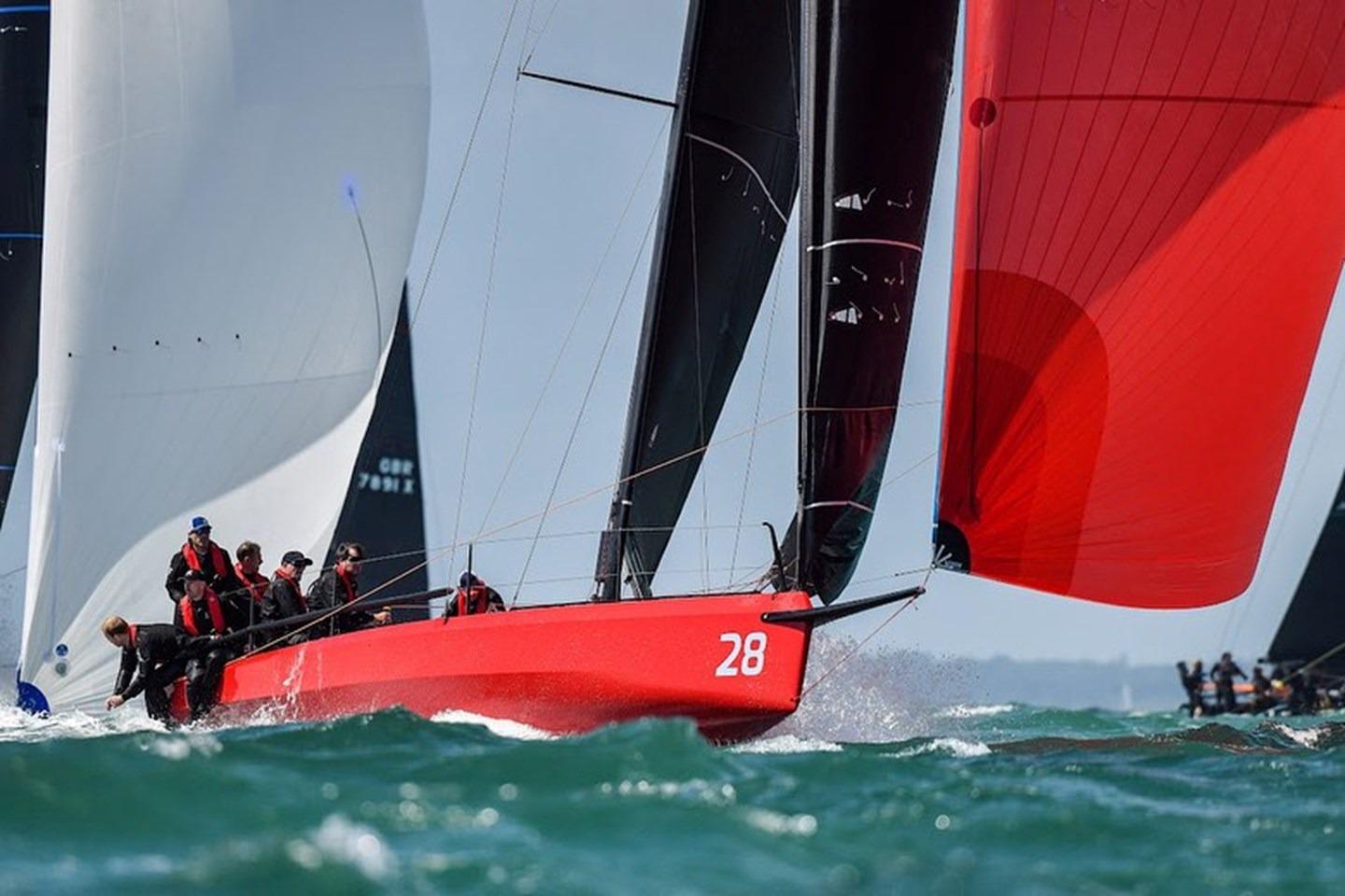 Red Cape 31 sailboat racing on open water, crew in action, vibrant sails, 2022 model.