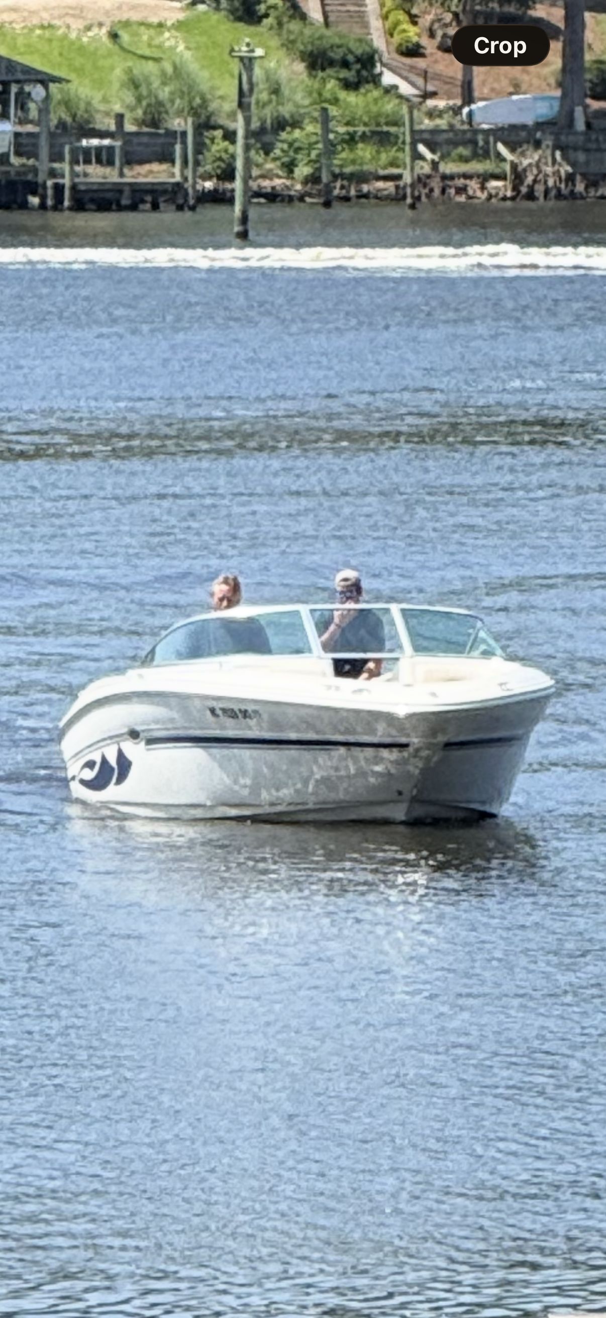 A white motorboat, Sea Ray 220 Select, cruising on calm waters with two people on board.