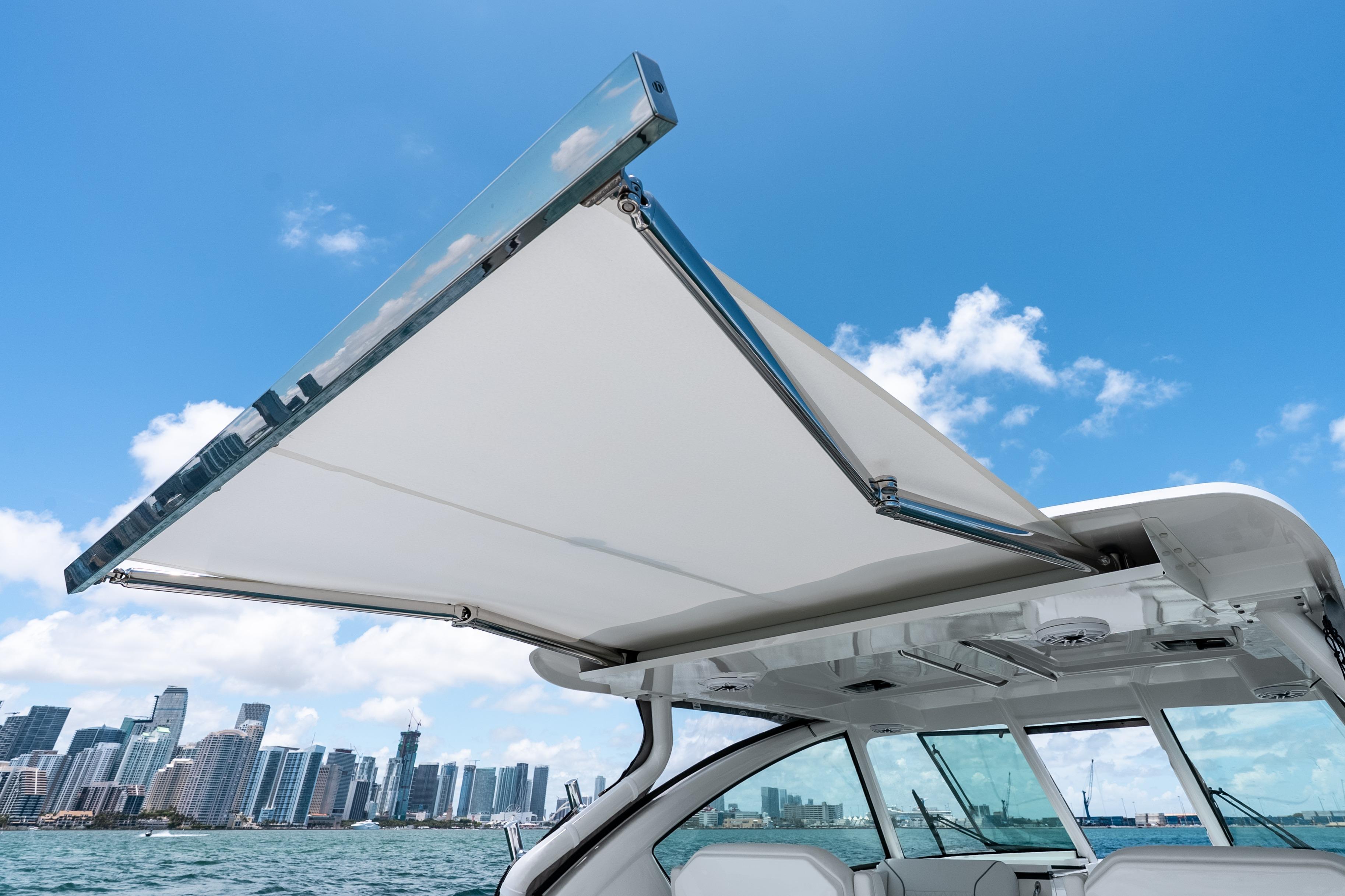 2026 Pursuit DC 326 Dual Console boat with retractable canopy, city skyline in background.