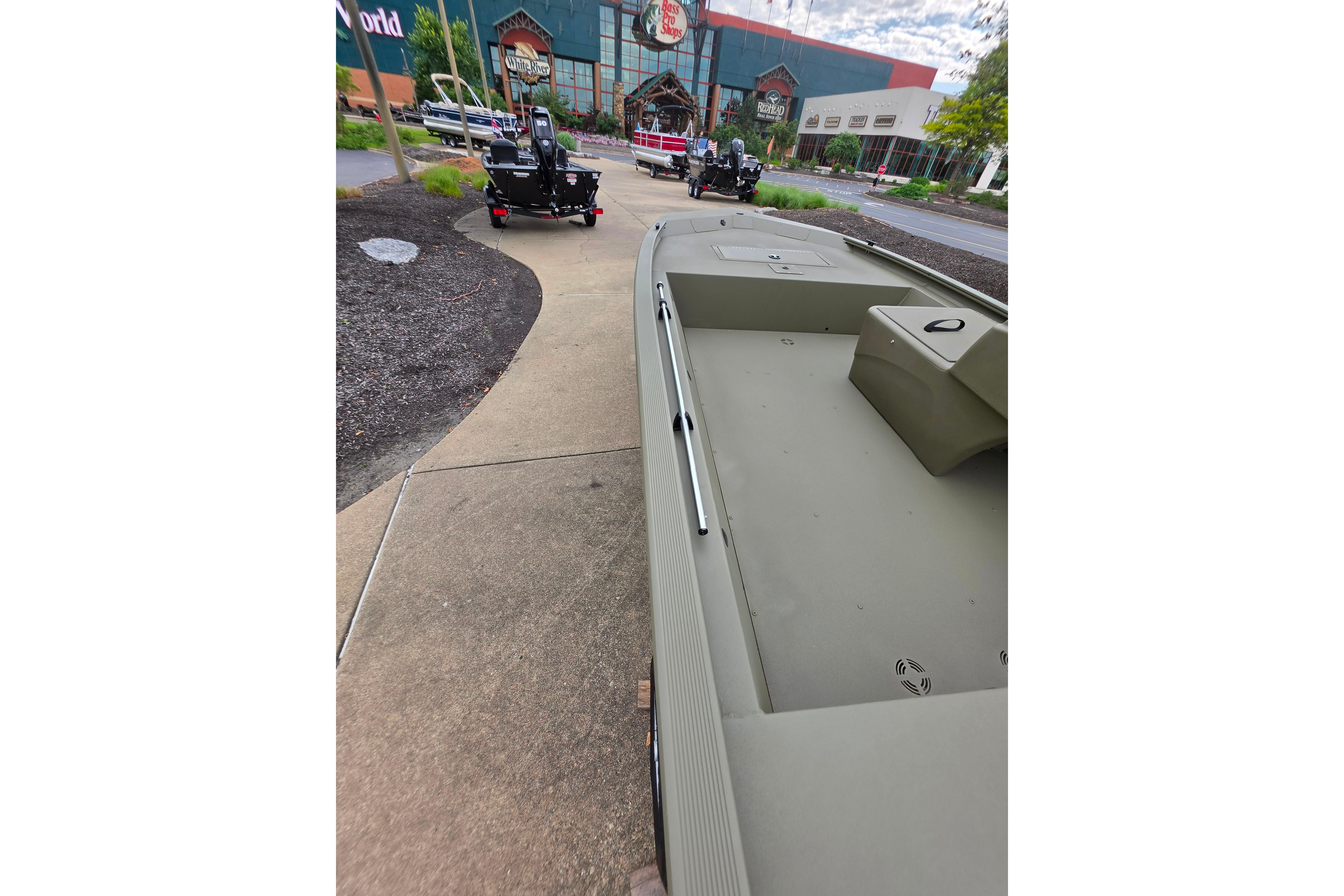 2026 Tracker Grizzly 1648 SC boat displayed outdoors near a store entrance.