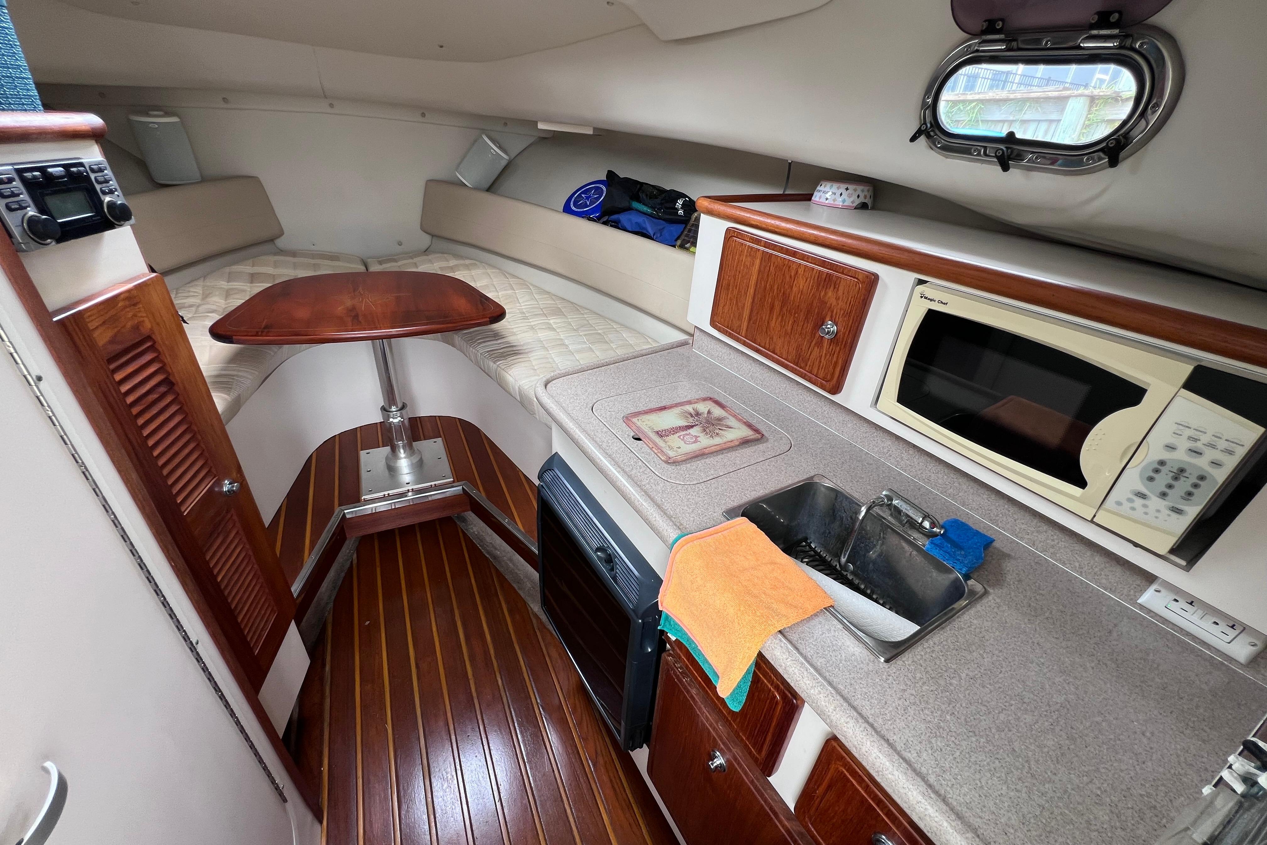 2005 Pursuit 3070 Offshore cabin interior with kitchenette, table, and seating area.