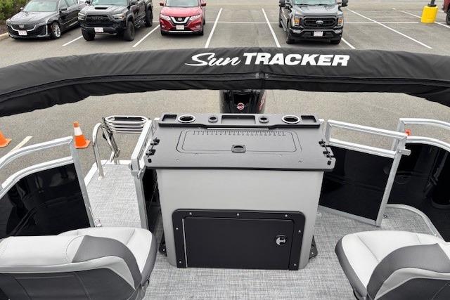 2026 Sun Tracker SportFish 22 DLX boat interior with seating and control panel in a parking lot.