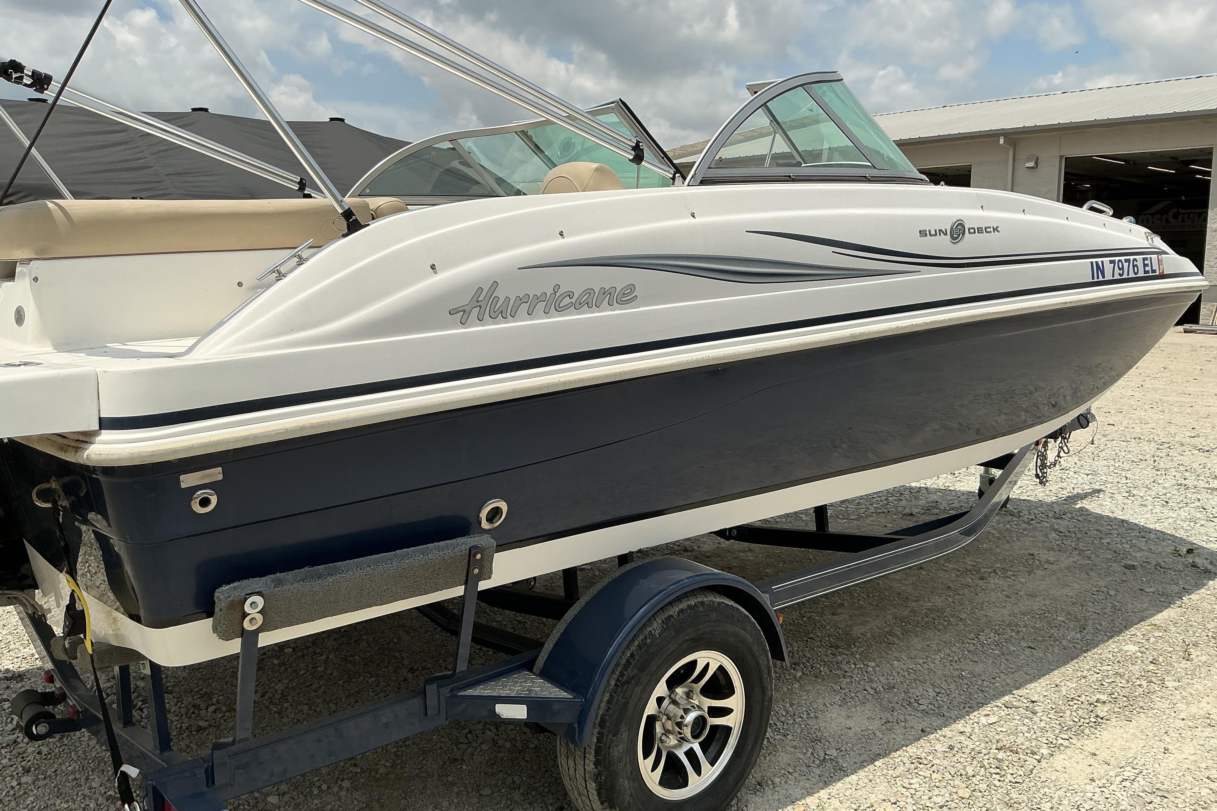 2015 Hurricane SunDeck 187 IO boat on trailer, parked outdoors under cloudy sky.