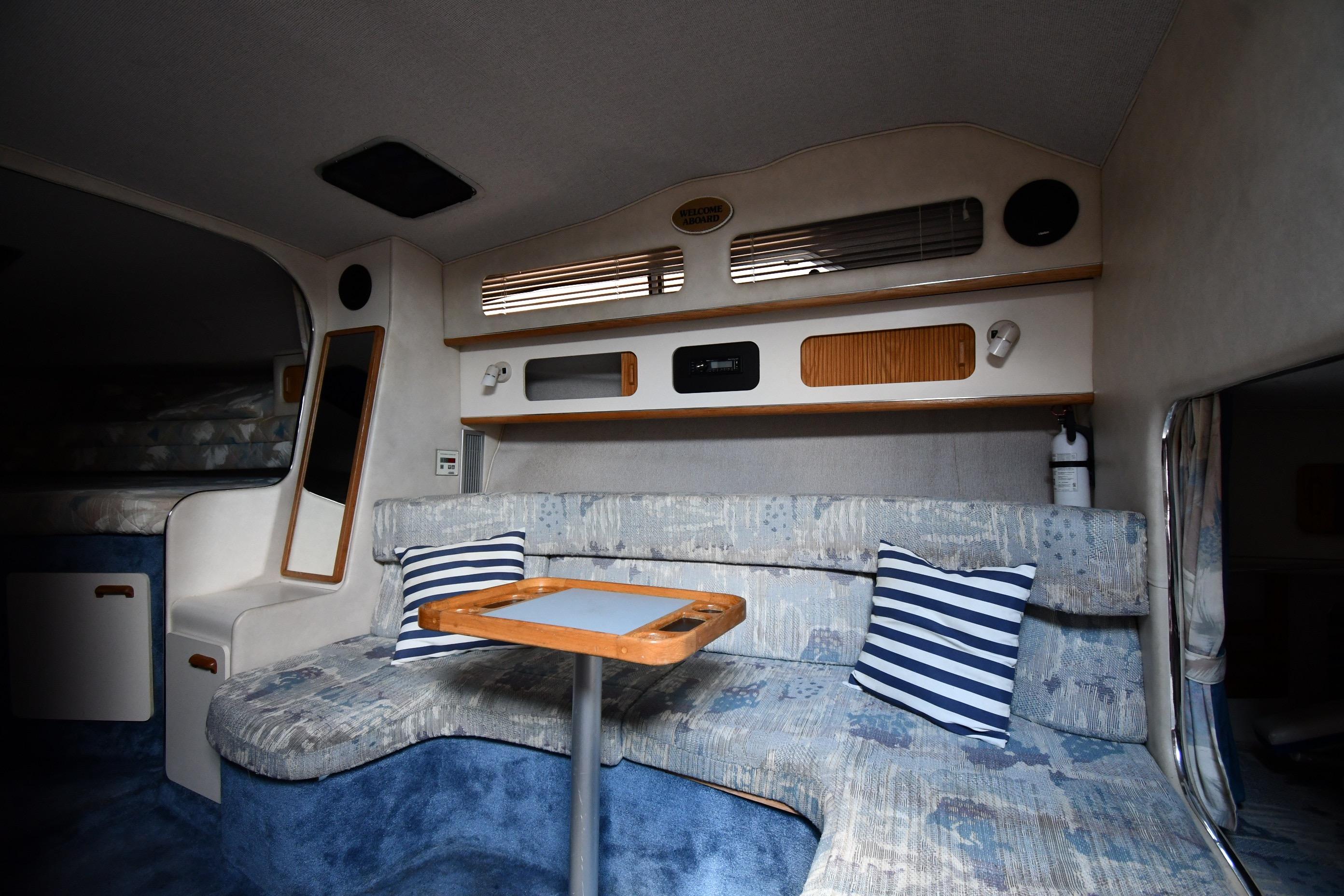 Interior of a 1993 Sea Ray 300 Sundancer boat with cozy seating and striped pillows.