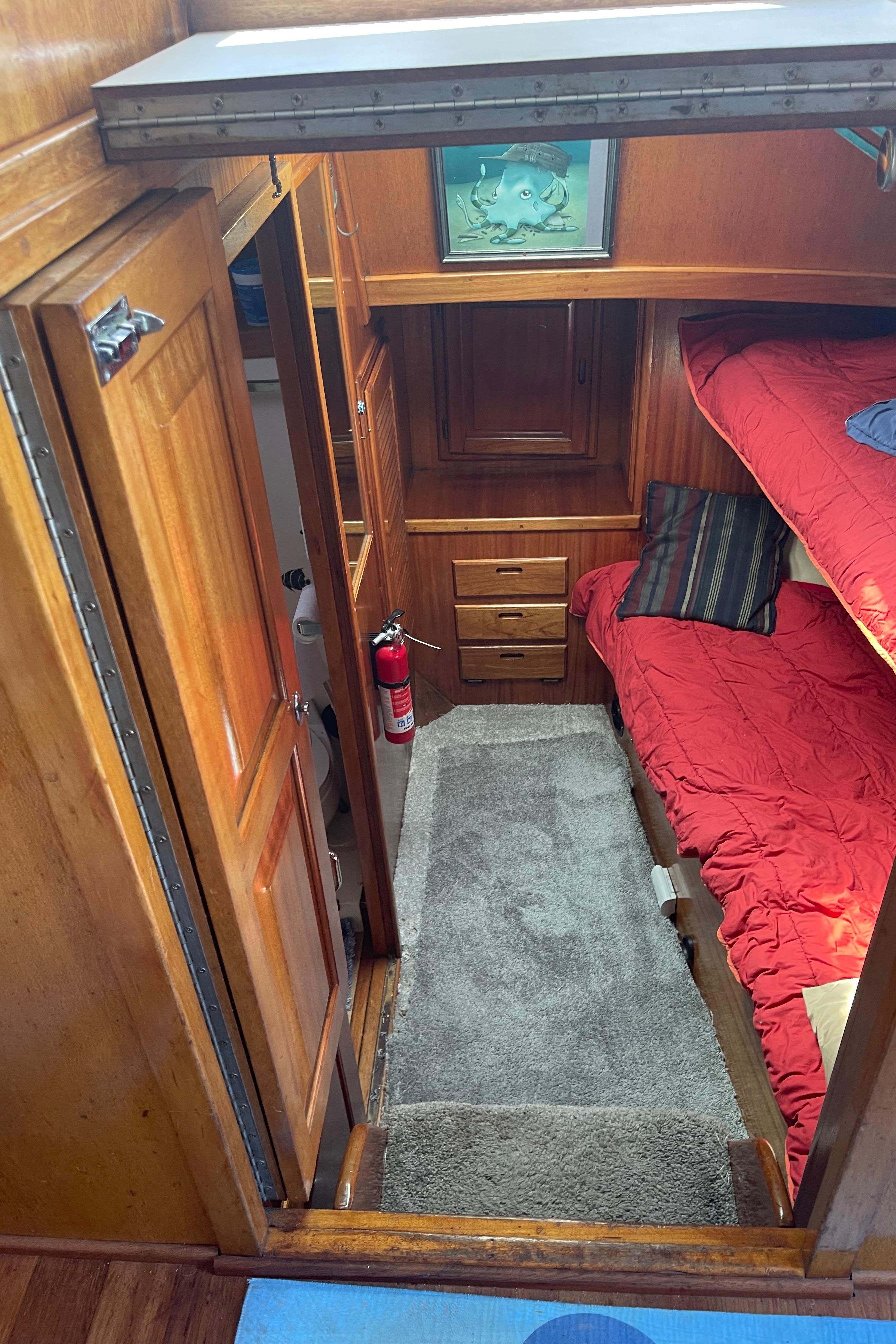 1978 Californian Tri-Cabin Trawler interior with wooden cabinetry and red bedding.