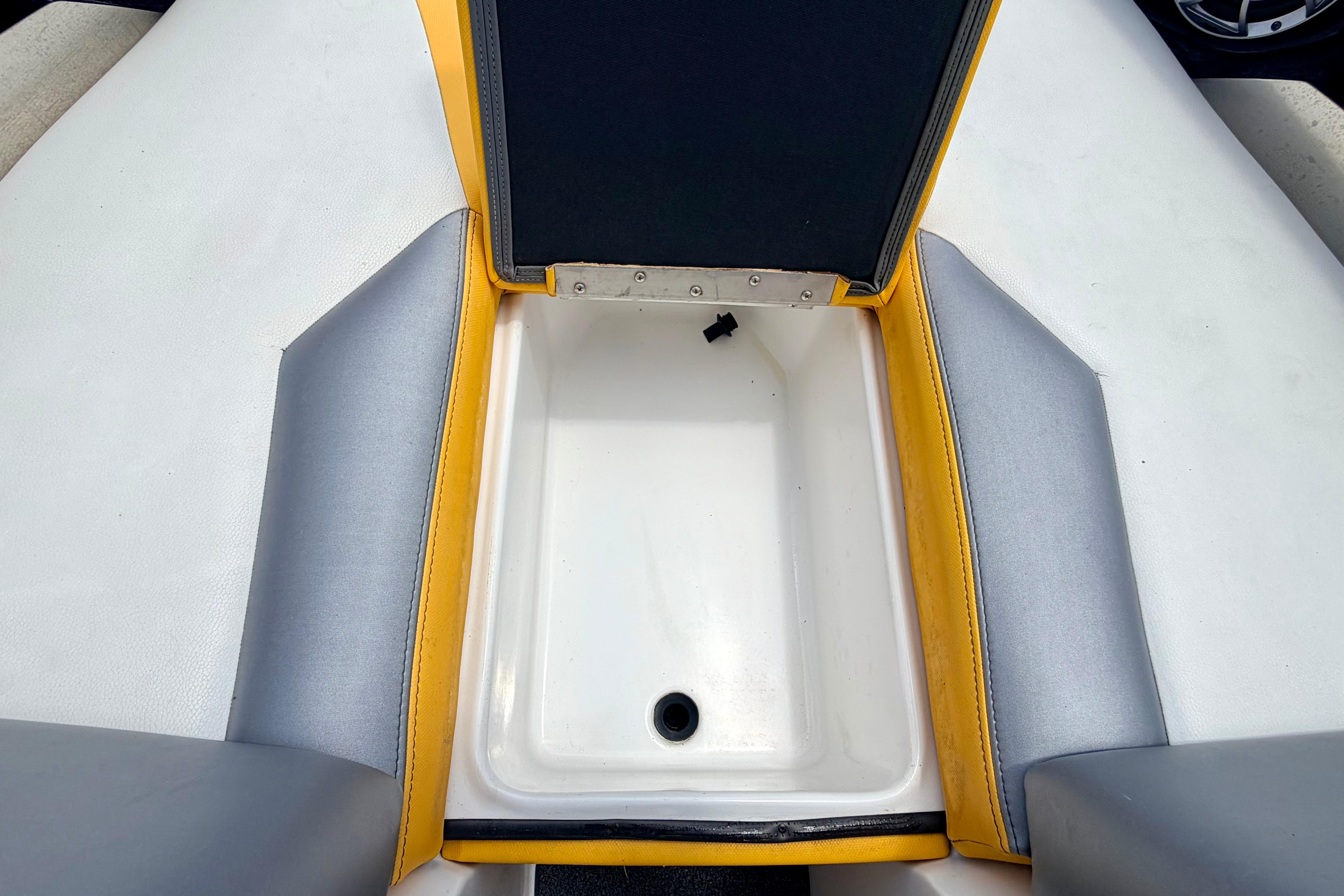 Open storage compartment in 2014 Tigé R20 boat with yellow and gray upholstery.