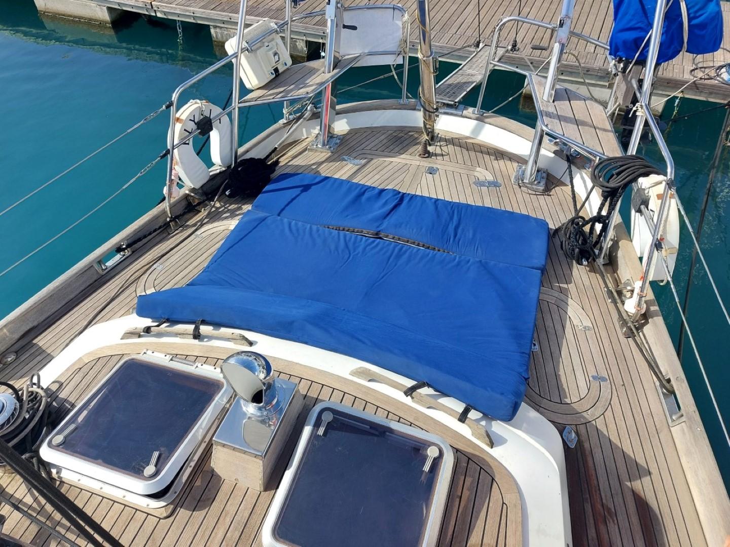 Sailboat deck with blue cover, Mystic 60, 1990 model, docked at marina.