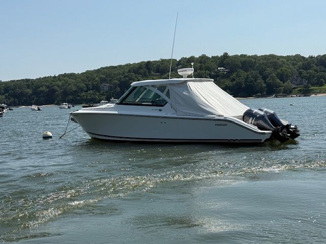 A white boat anchored on calm water, surrounded by green hills.