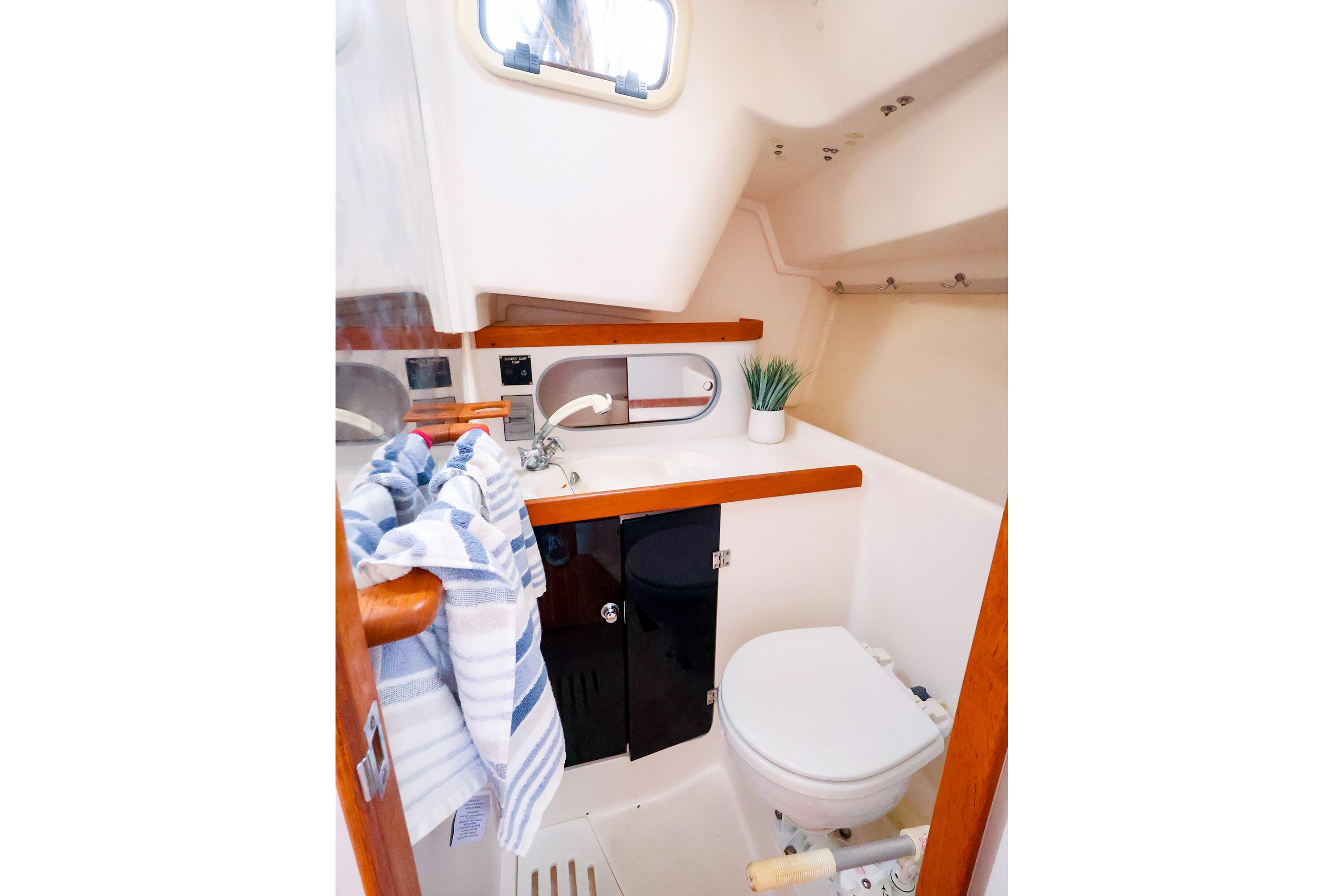 2001 J Boats J/32 yacht bathroom with sink, toilet, mirror, and striped towel.