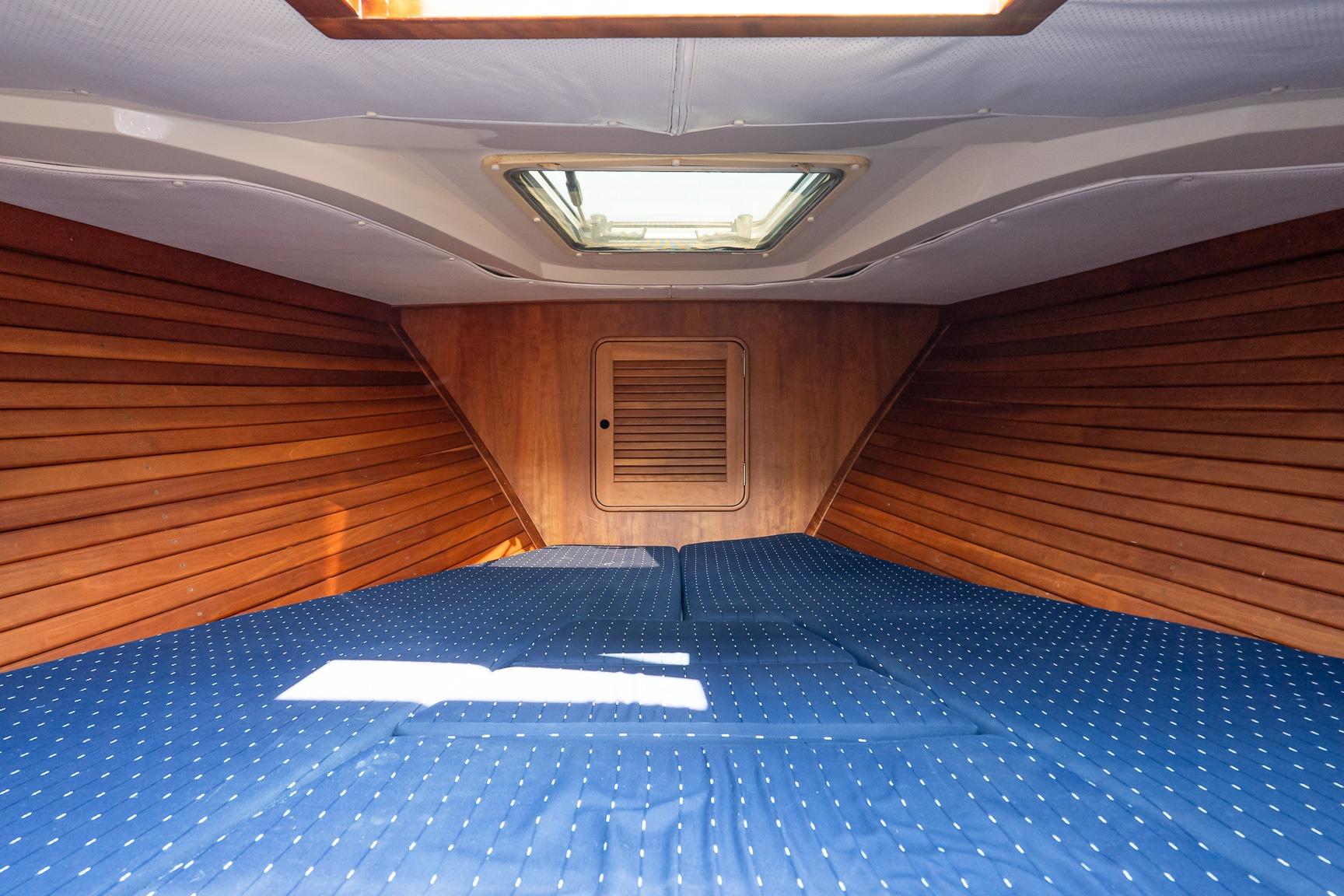 Interior cabin of 2005 Hinckley Talaria 29R with wood paneling and blue bedding.