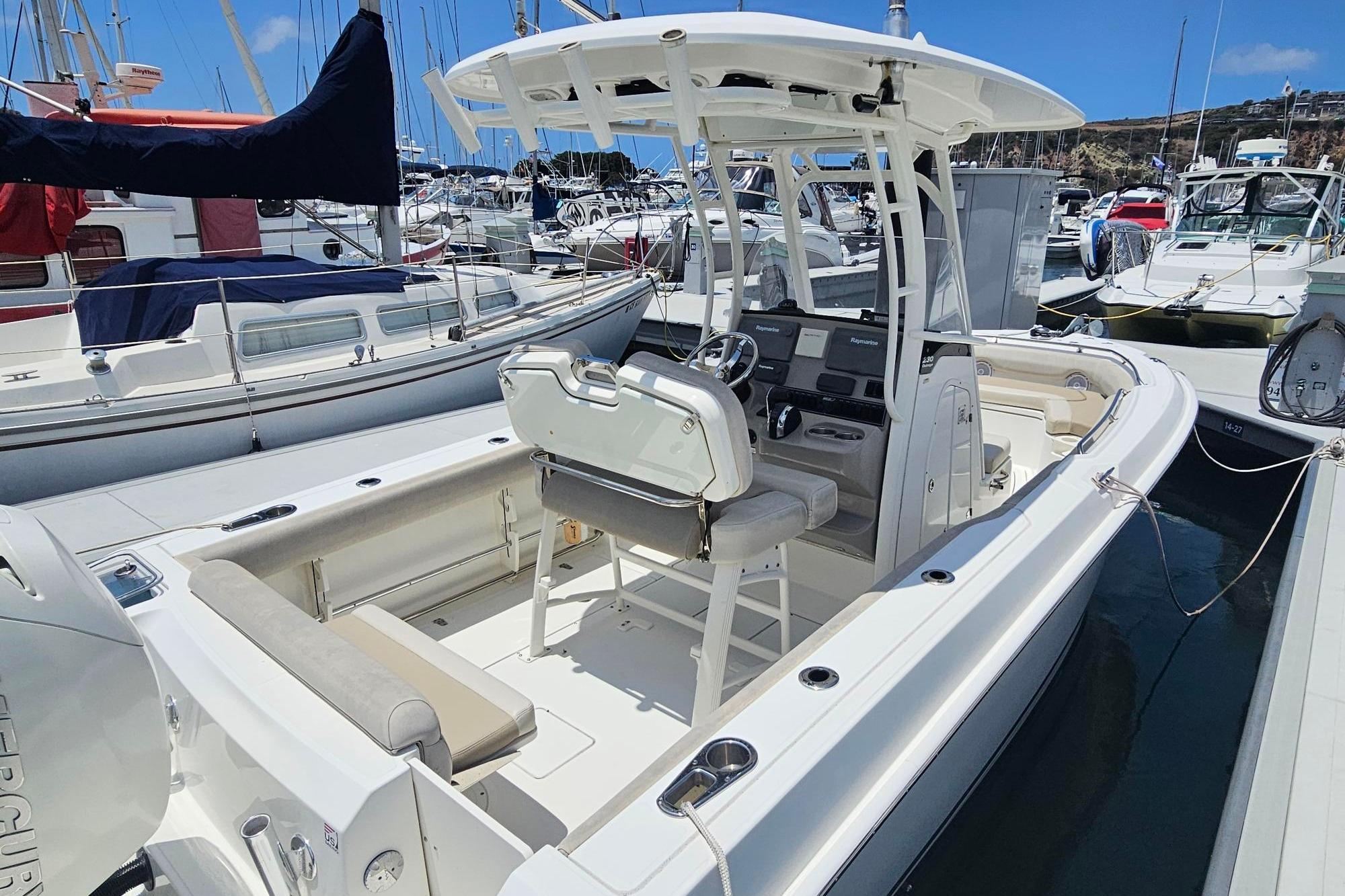 2017 Boston Whaler 230 Outrage boat docked in a marina, showcasing sleek design and spacious seating.