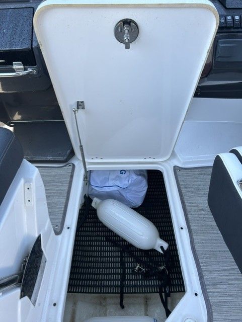 An open storage compartment on a boat with a fender and a bag.