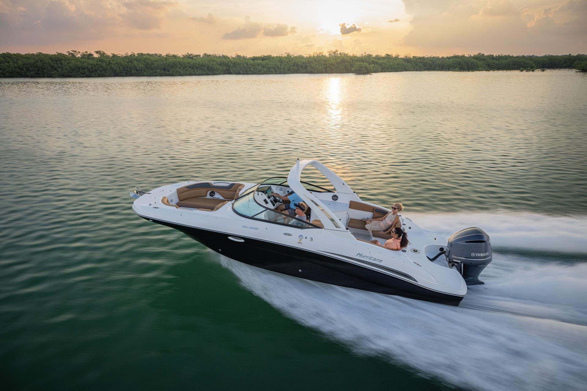 2026 Hurricane SunDeck 2690 OB cruising on serene waters at sunset.