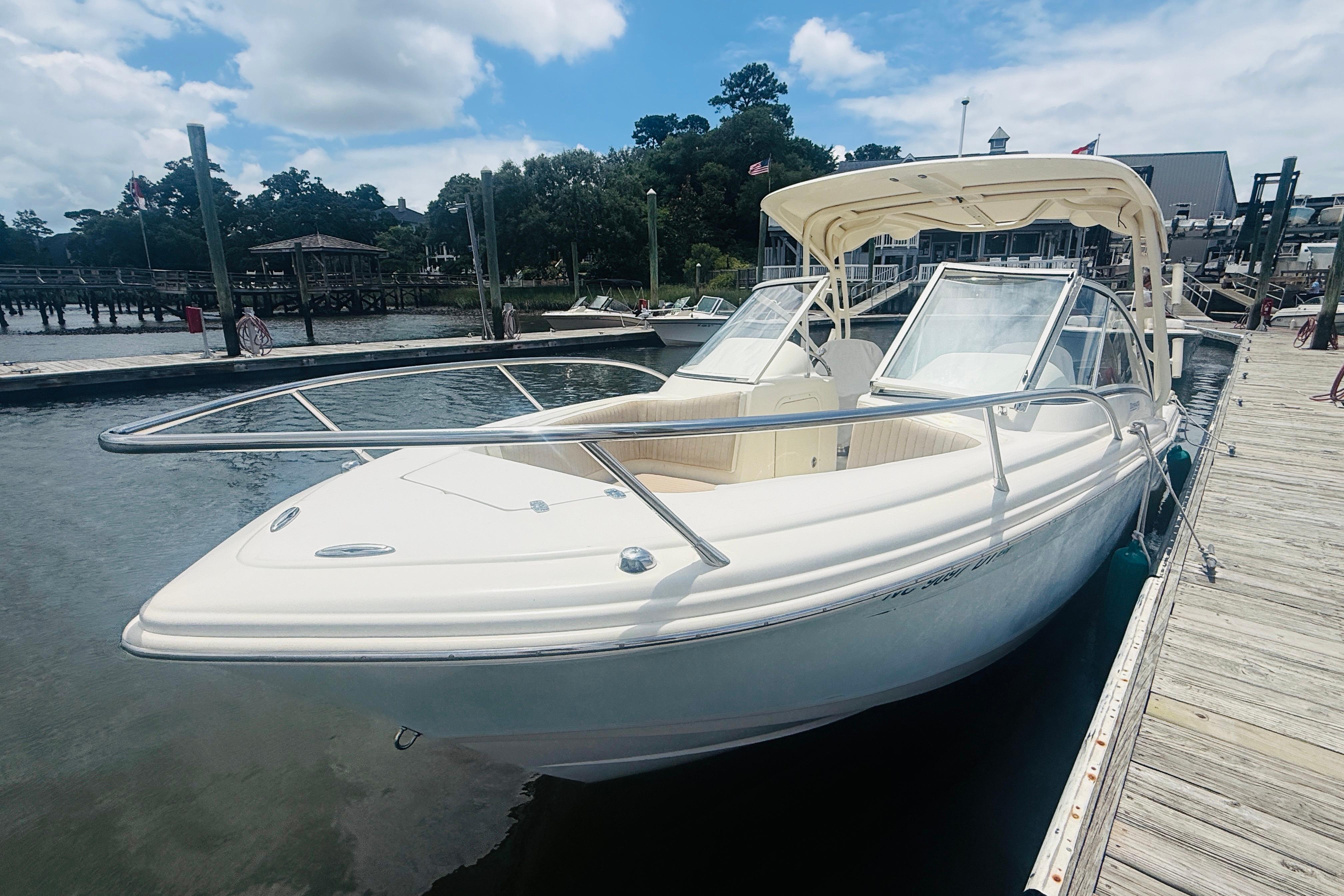 2012 Scout 245 Dorado boat docked at a marina under a partly cloudy sky.