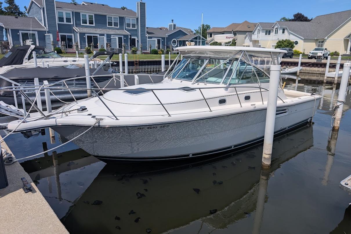 2000 Pursuit 3400 Express boat docked in a marina with waterfront homes.