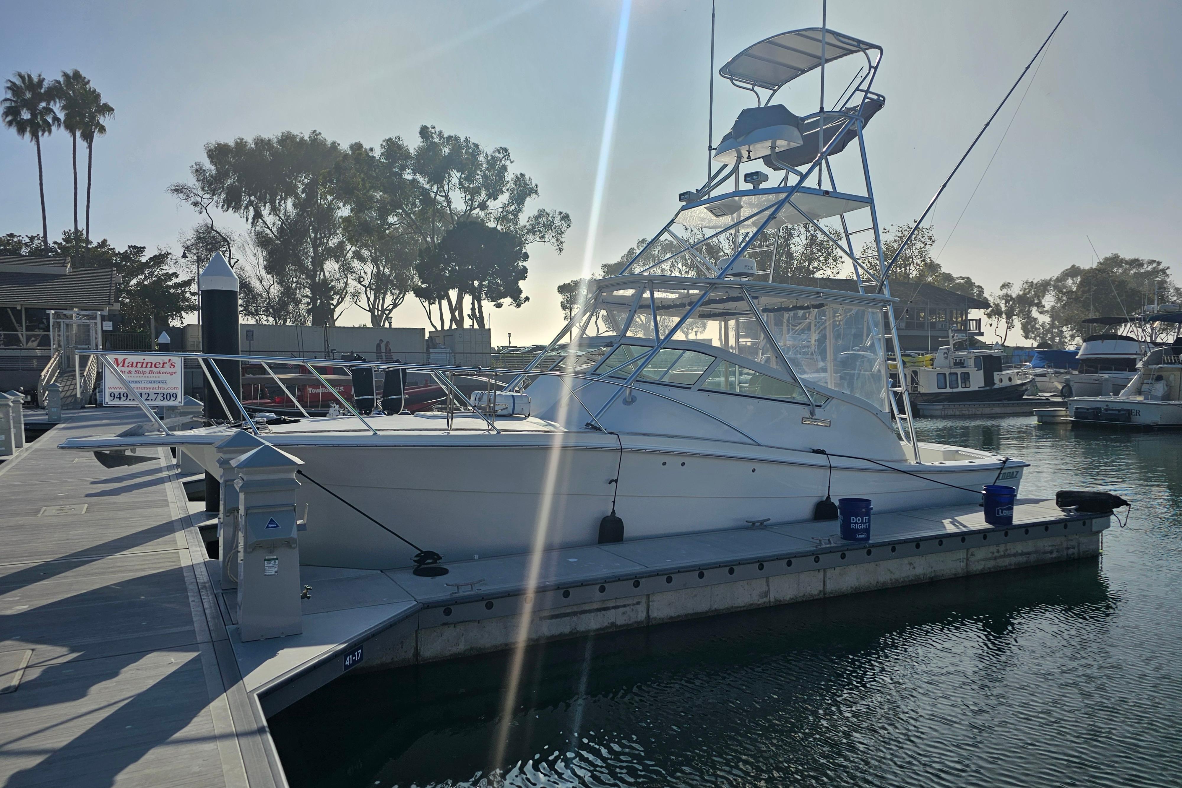 2003 Topaz 32 Express boat docked at marina with clear sky and trees in background.