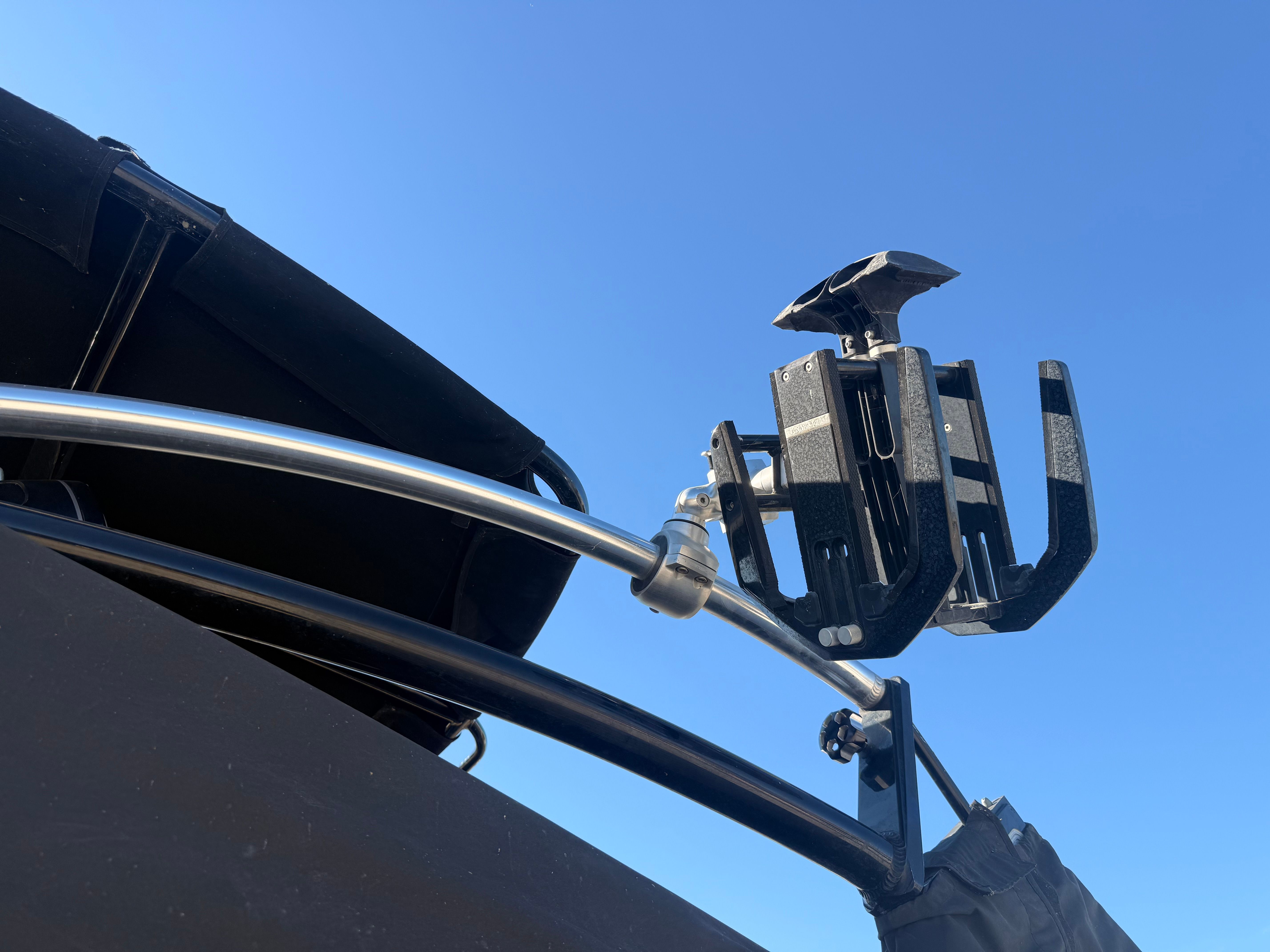 Close-up of a black boat with a metal bracket and mount against a blue sky.