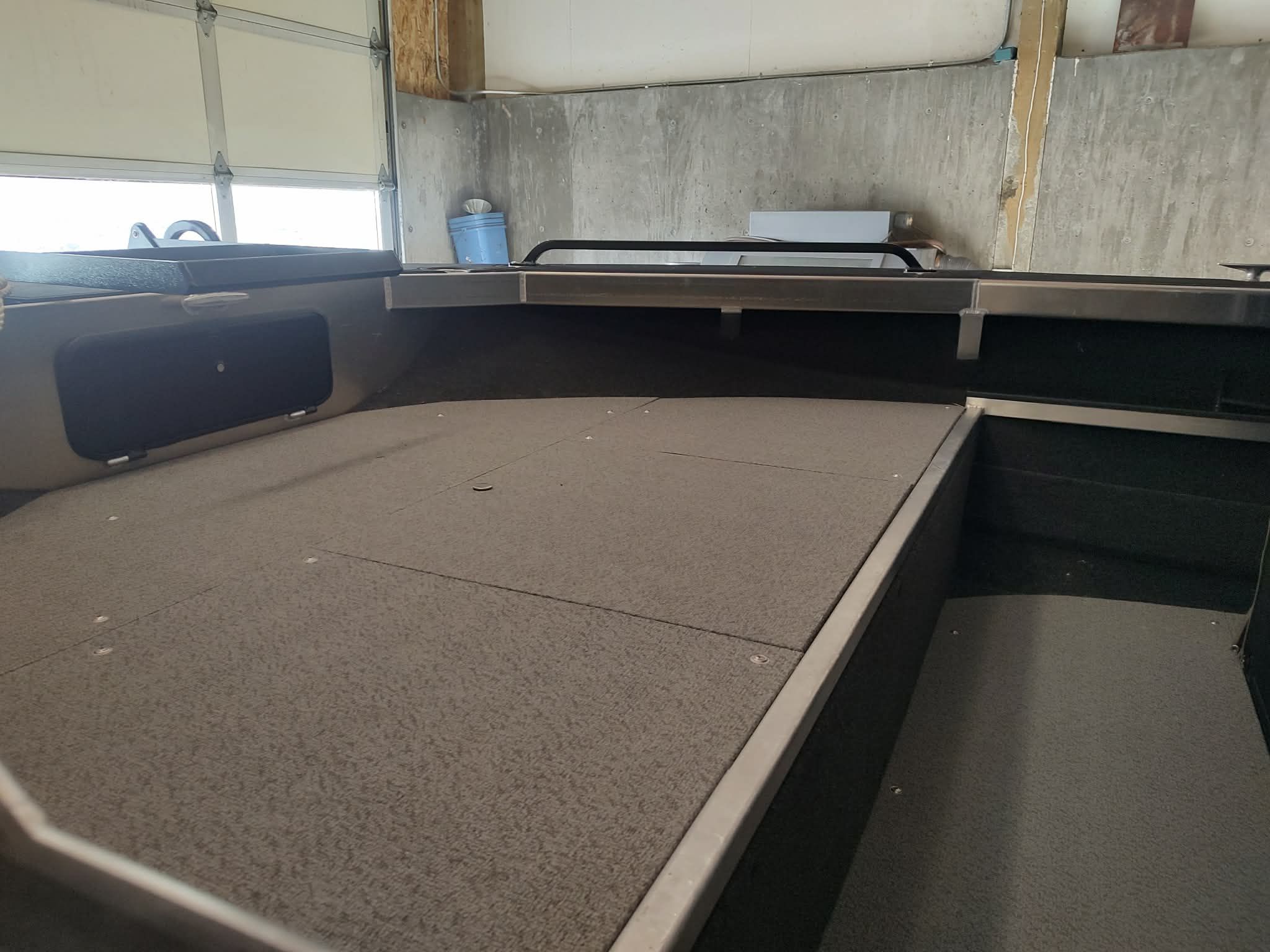 Interior view of a Custom Weld 23' sled t-top boat in a garage.
