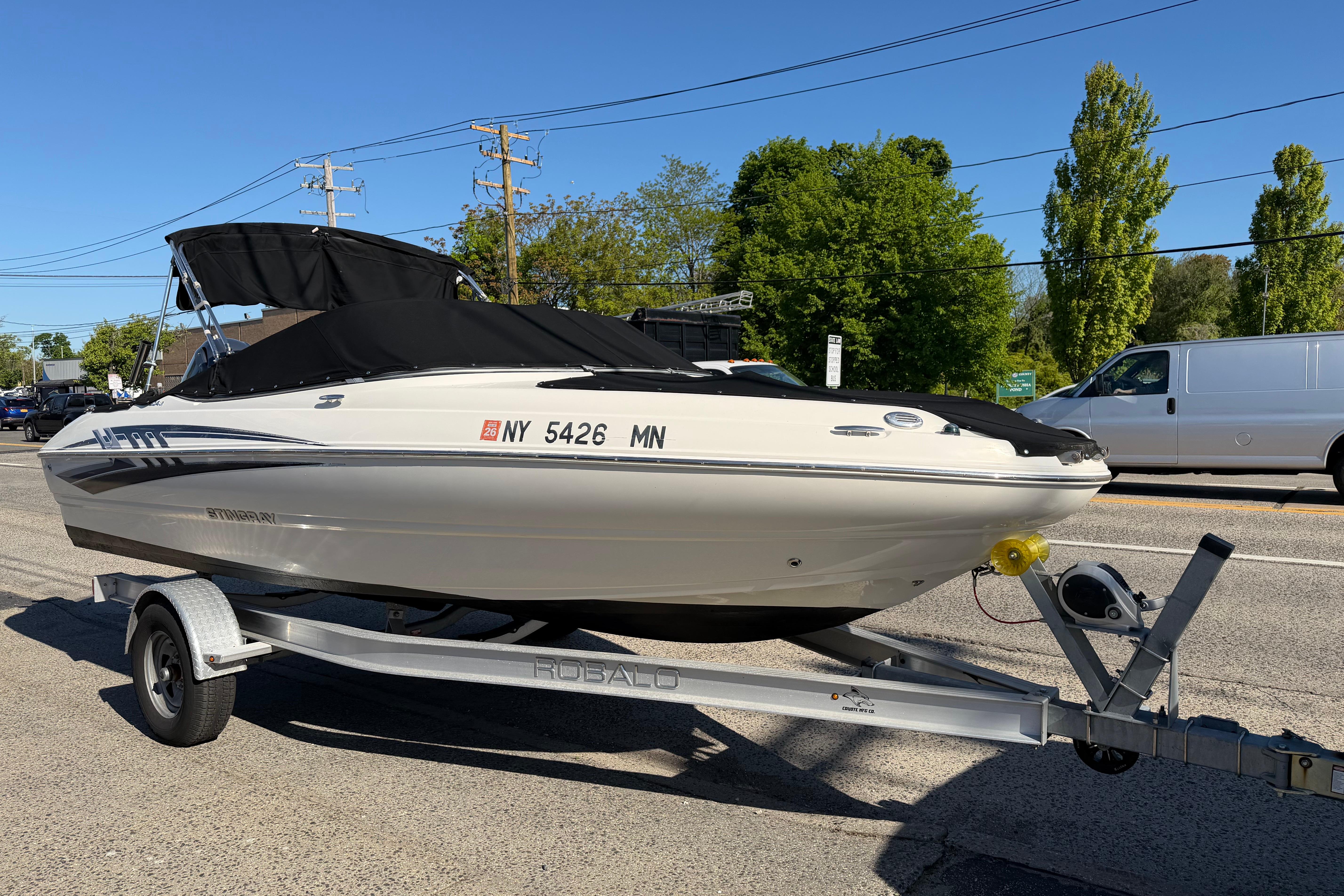 2018 Stingray 204 LR boat on trailer, parked outdoors under clear blue sky.